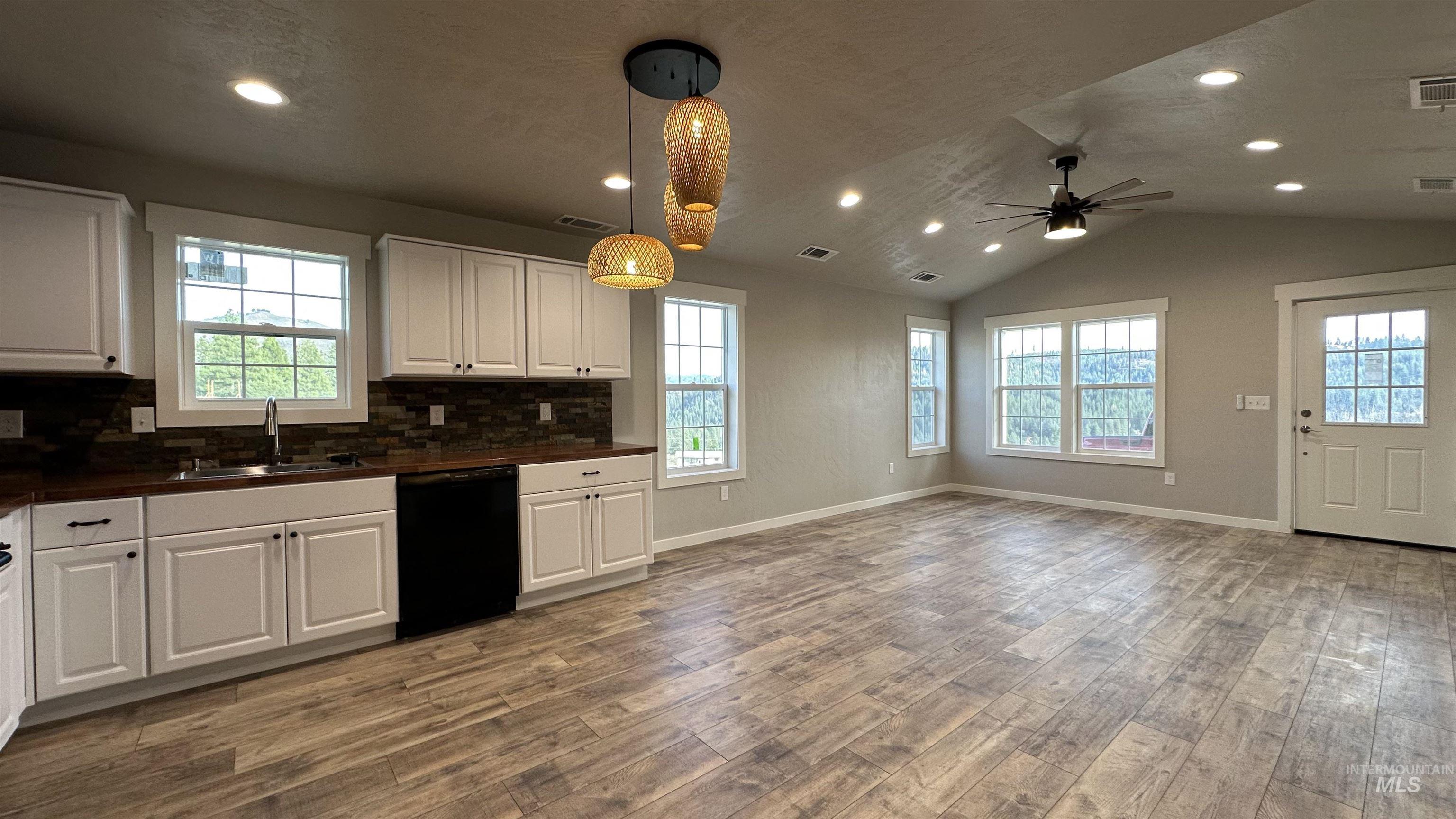 Kitchen with hanging light fixtures, white cabinetry, dark countertops, recessed lighting, and backsplash