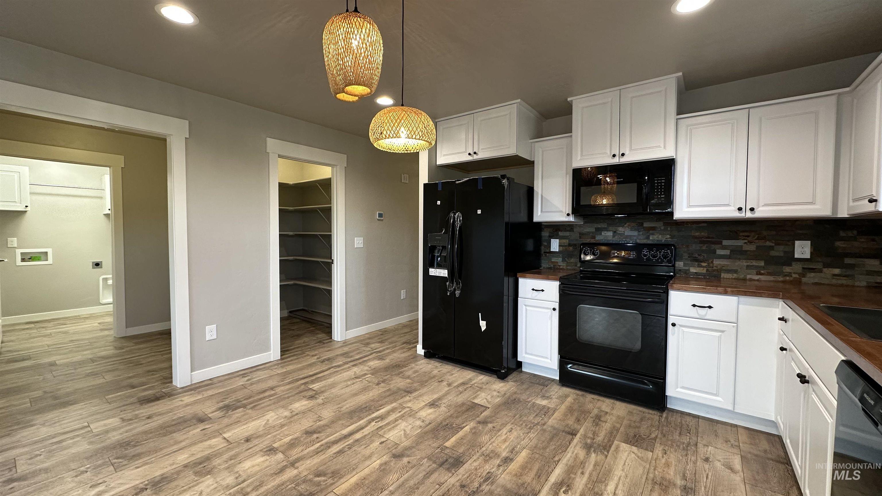Kitchen featuring black appliances, white cabinets, backsplash, recessed lighting, and light wood-style flooring