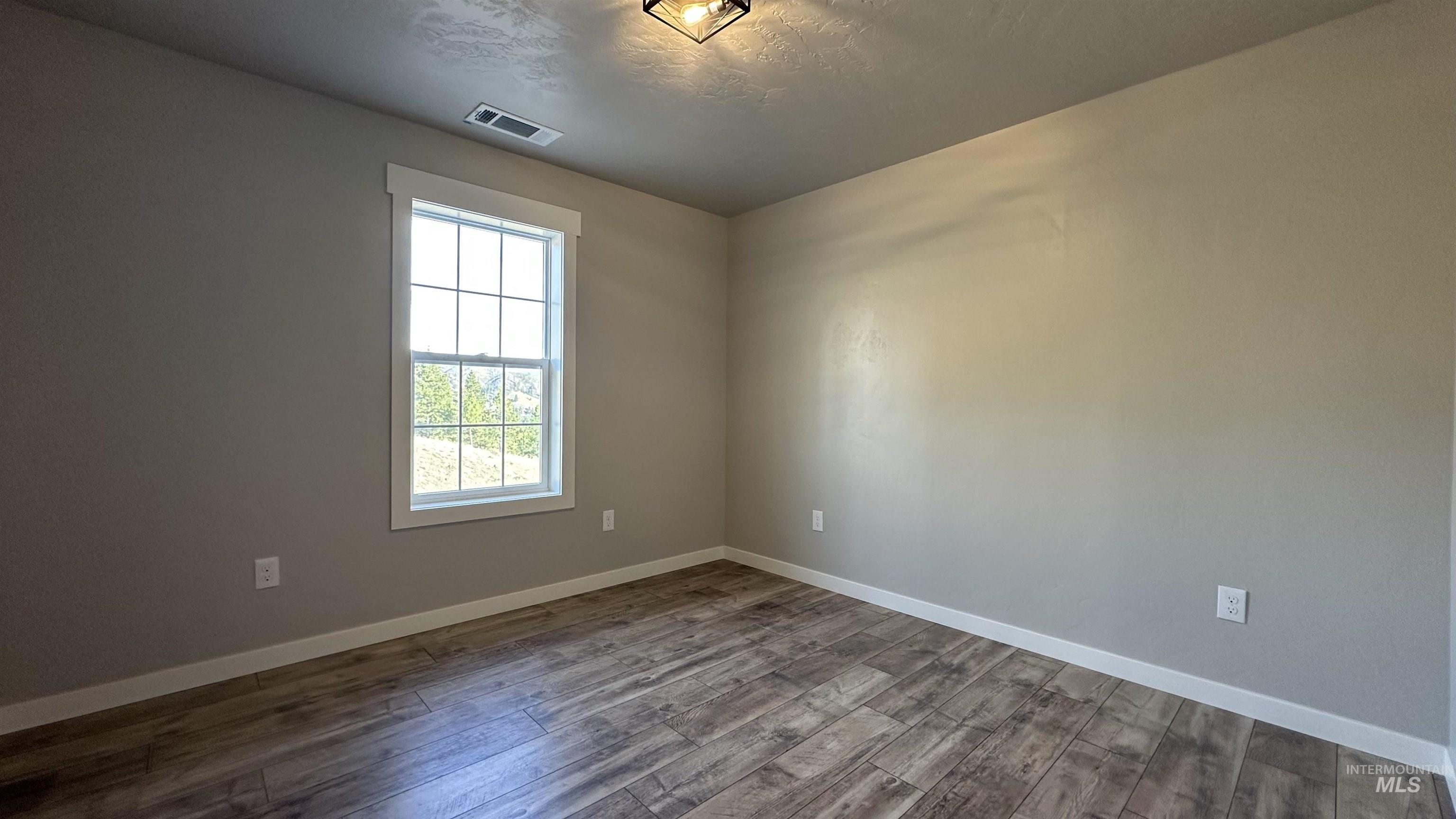 Spare room featuring wood finished floors and a textured ceiling