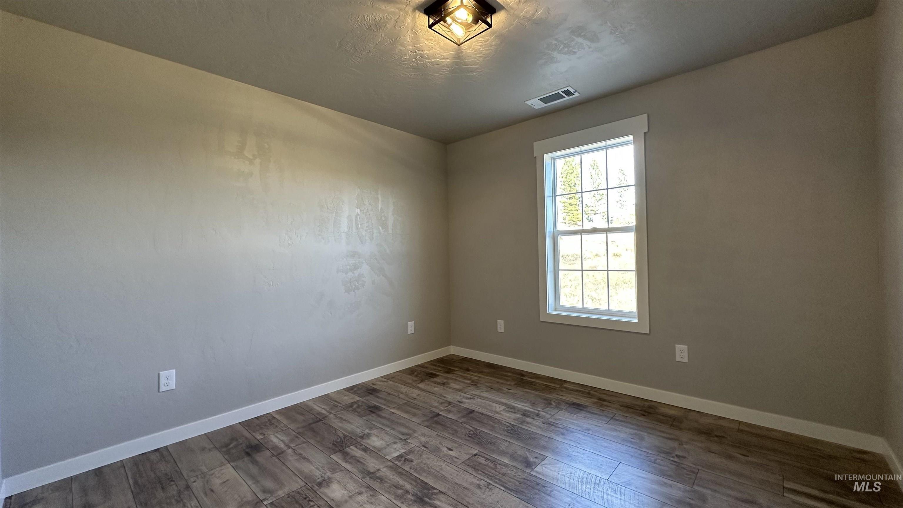 Empty room with dark wood finished floors and a textured ceiling