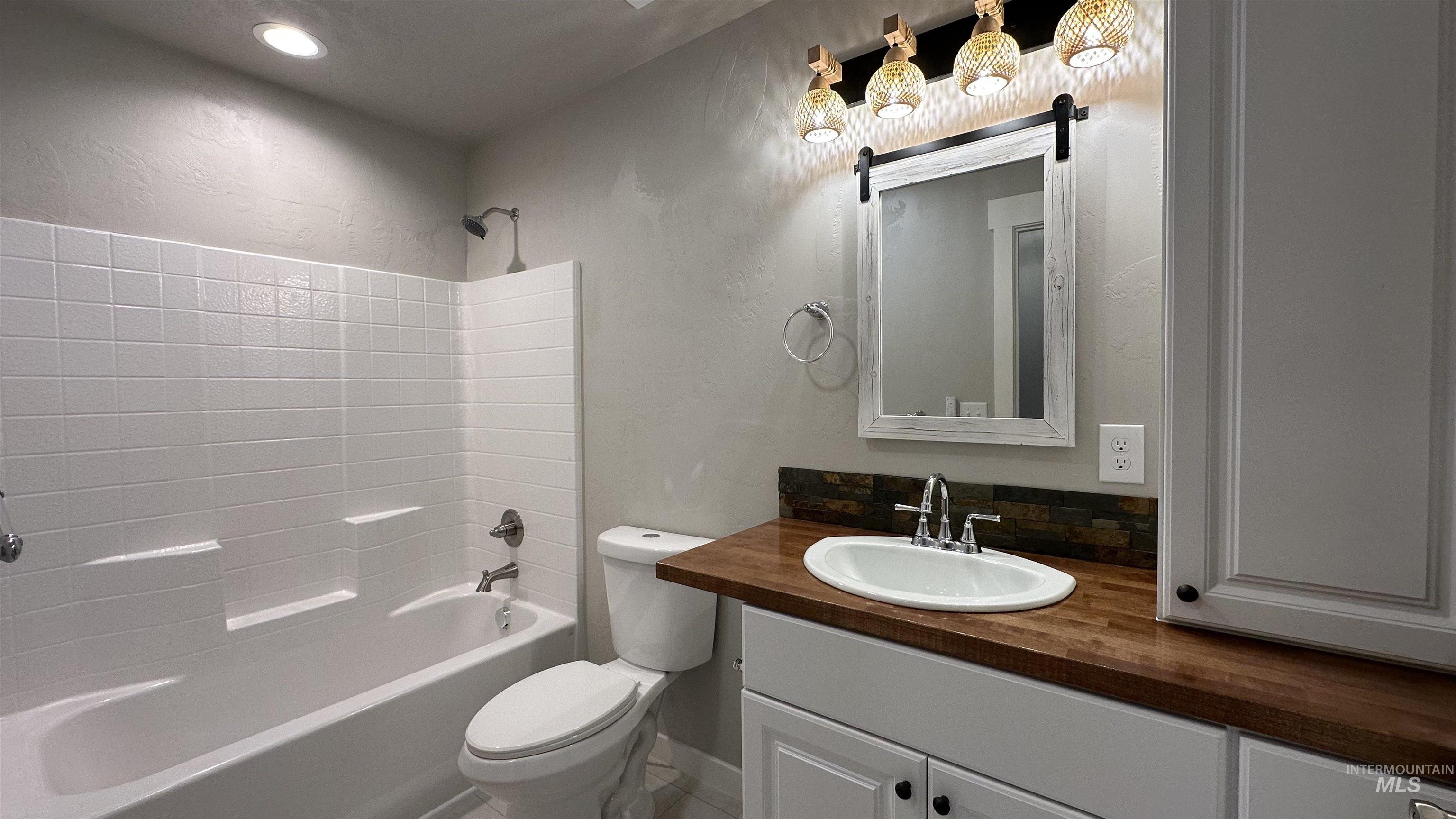 Bathroom featuring shower / washtub combination, vanity, and a textured wall