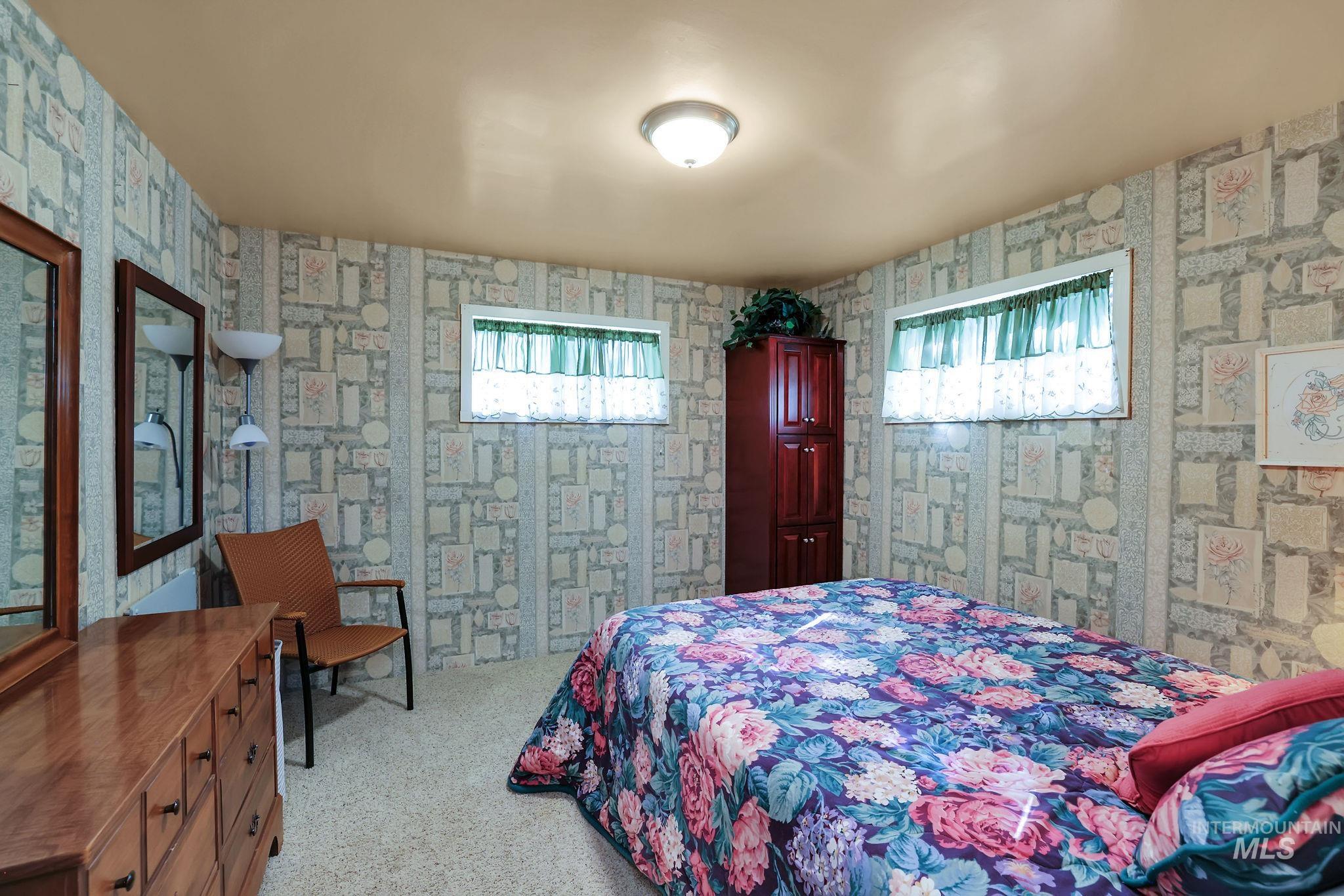 Bedroom with wallpapered walls and light colored carpet
