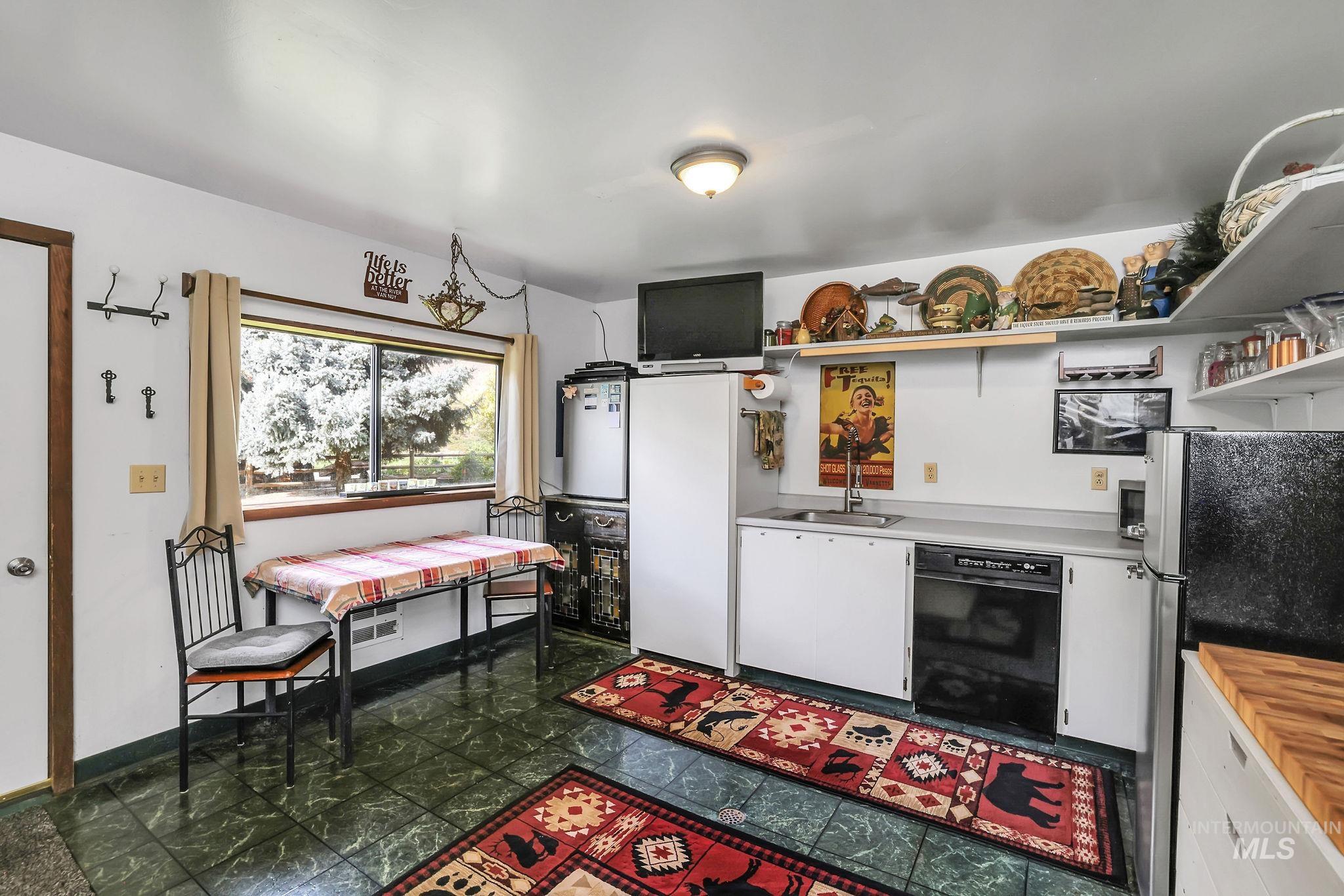 Kitchen with open shelves, freestanding refrigerator, light countertops, white cabinets, and dishwasher