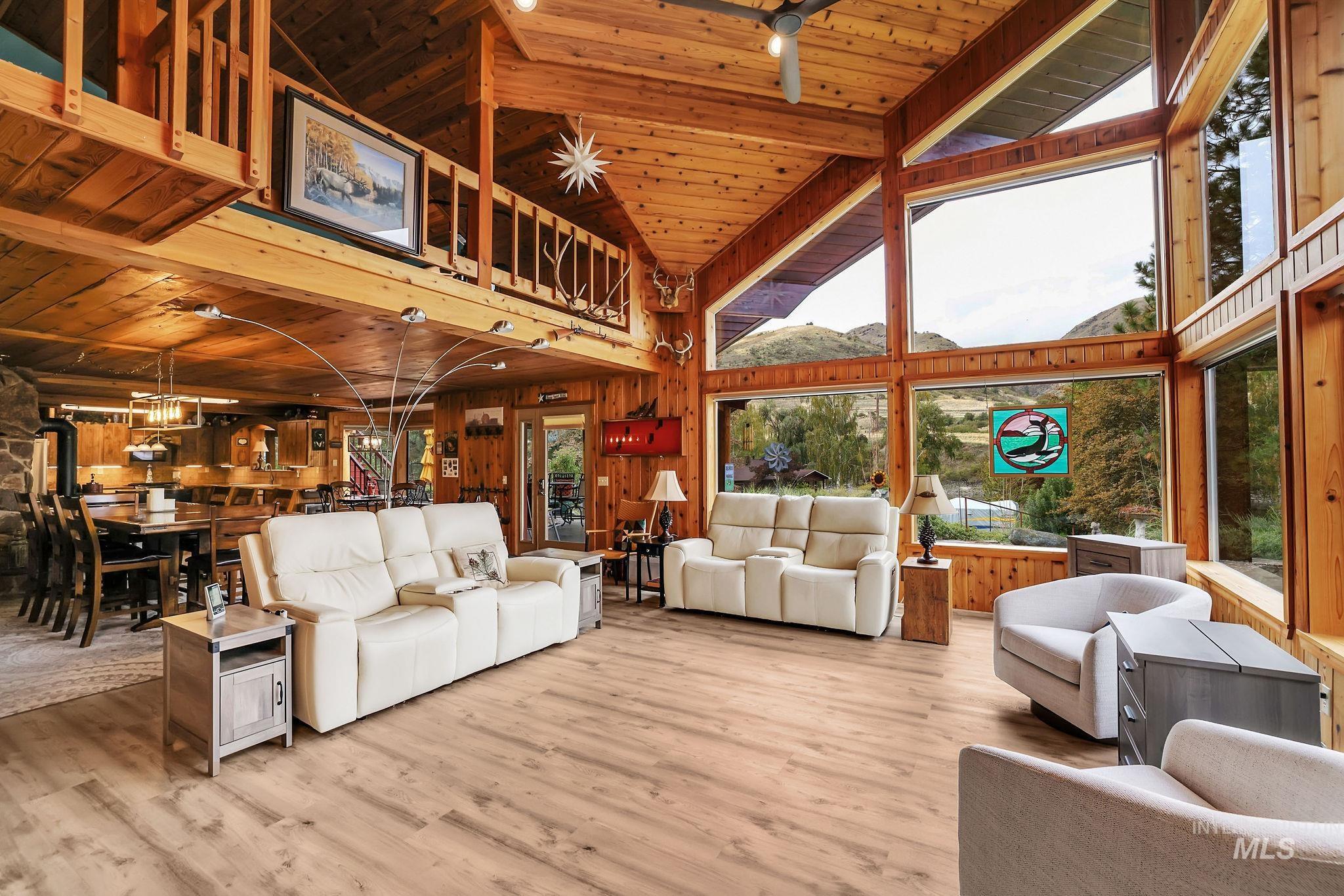 Living room with wooden ceiling, wooden walls, high vaulted ceiling, and wood finished floors