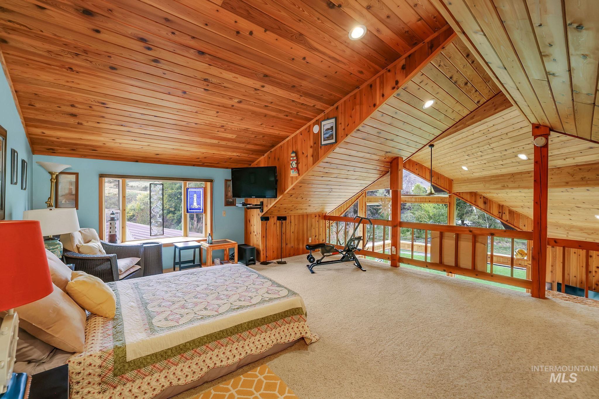 Loft with vaulted ceiling, wood ceiling, recessed lighting, and wood walls
