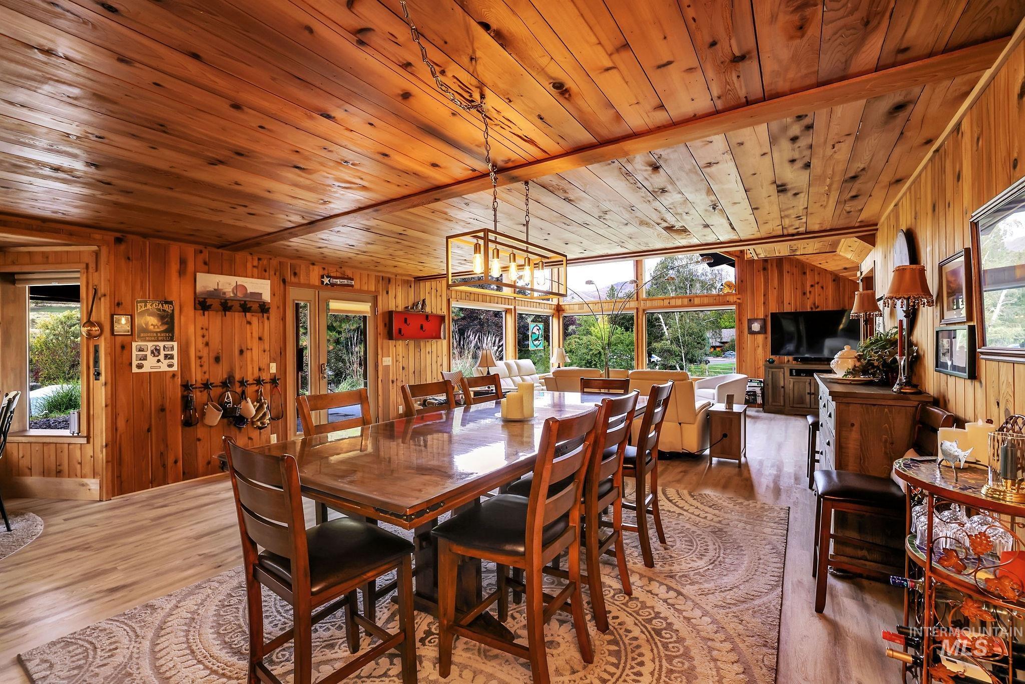 Dining space with wooden walls, wood finished floors, a chandelier, and wood ceiling