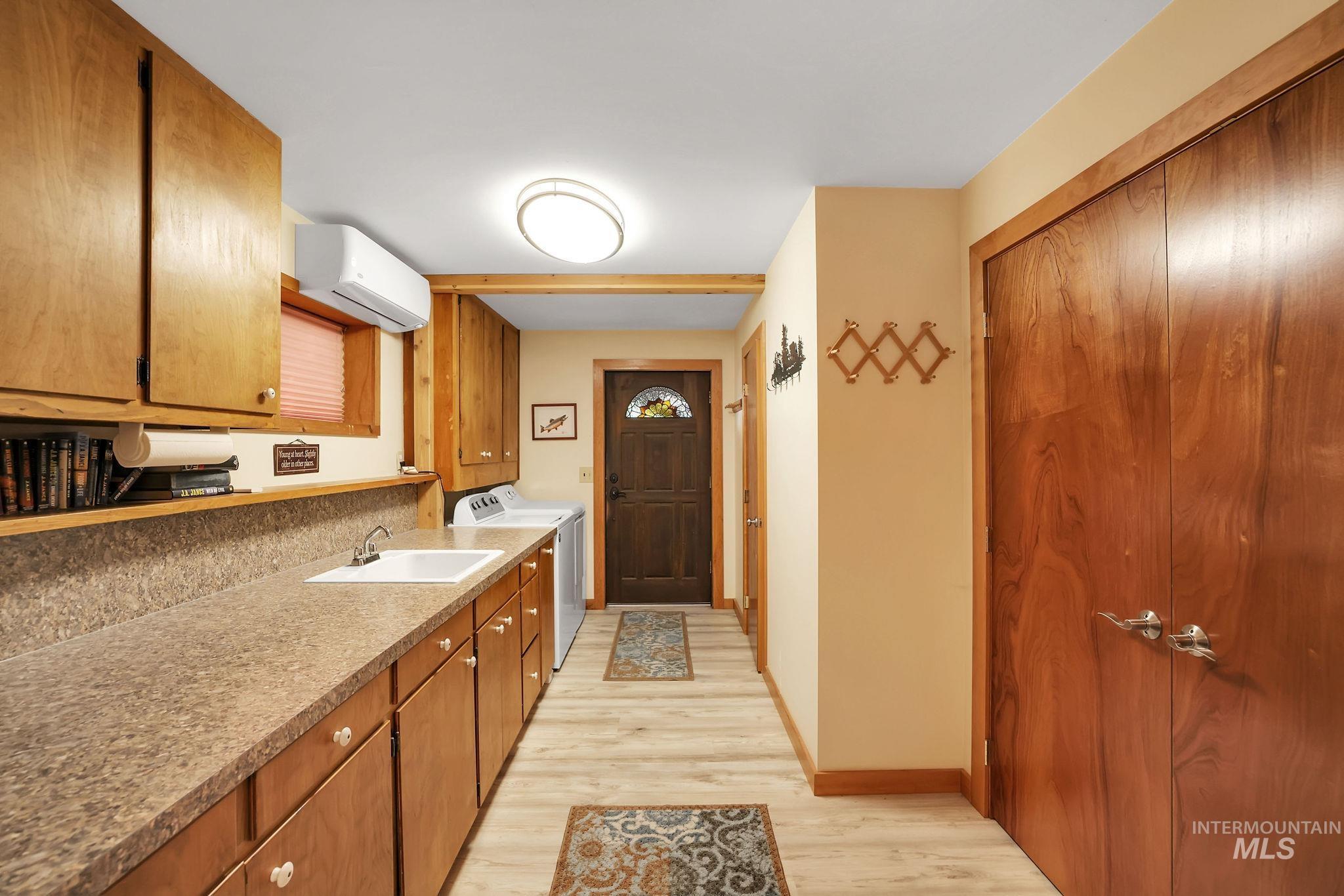 Washroom featuring light wood-style flooring, washer and clothes dryer, and cabinet space