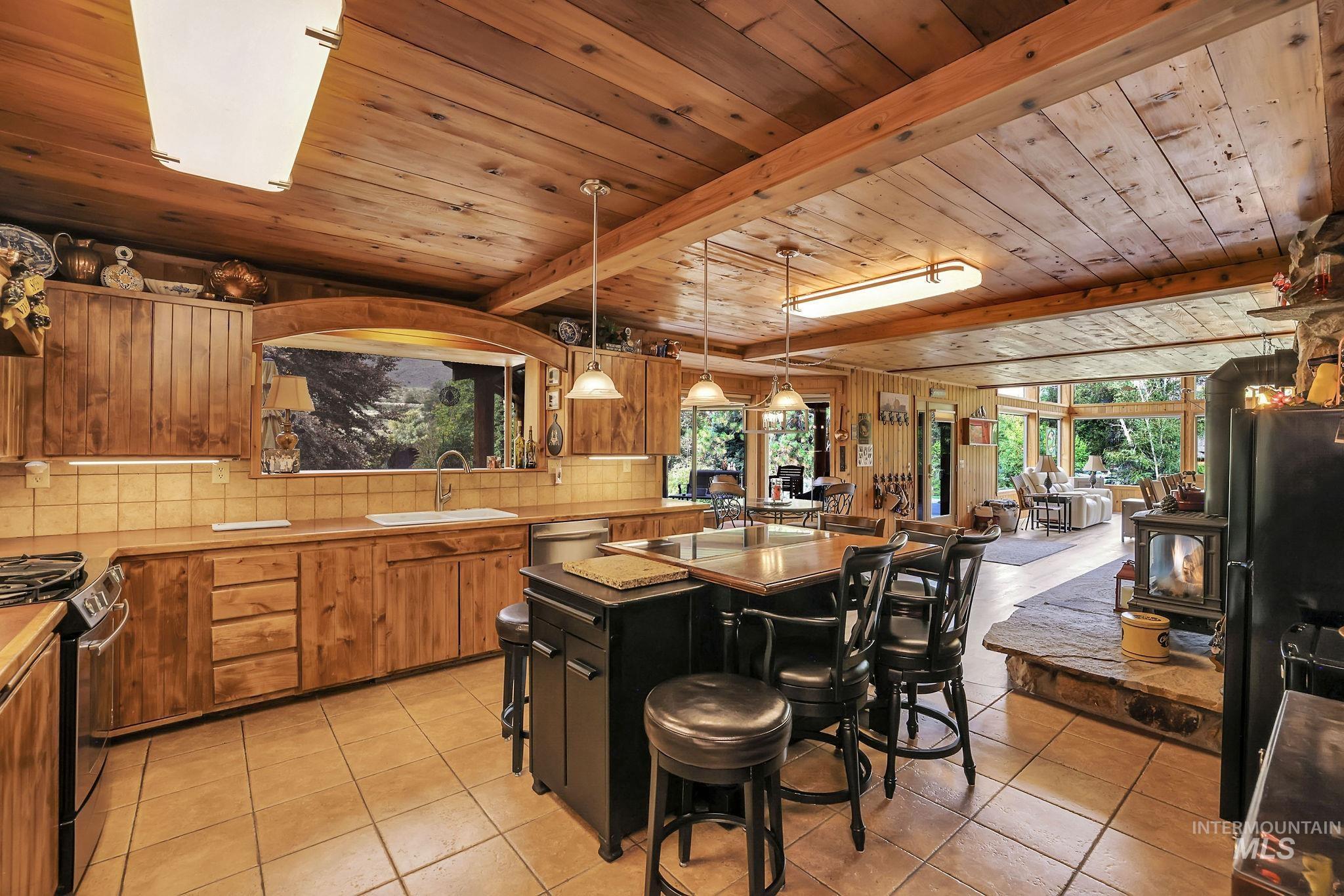 Kitchen with light tile patterned floors, plenty of natural light, pendant lighting, and a wood ceiling with exposed beams