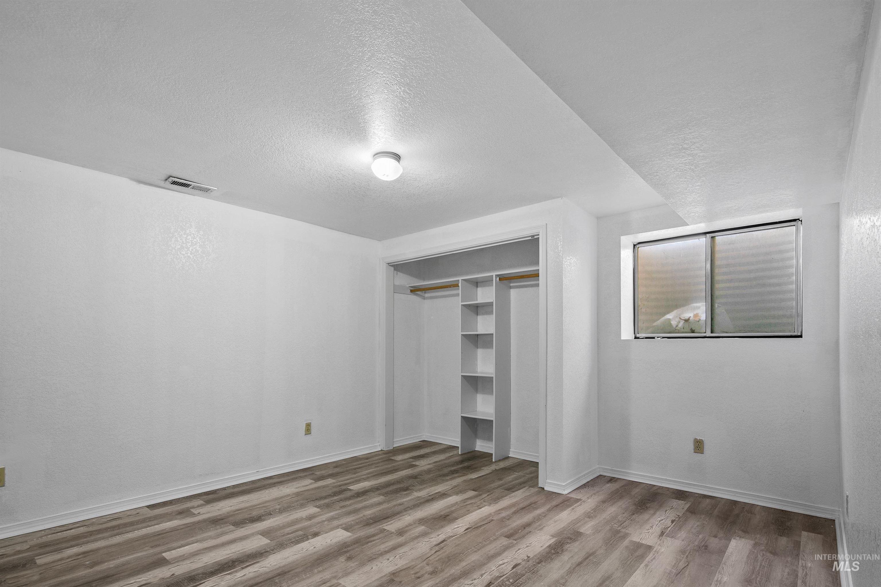 Unfurnished bedroom with a textured ceiling, light wood-style floors, and a closet