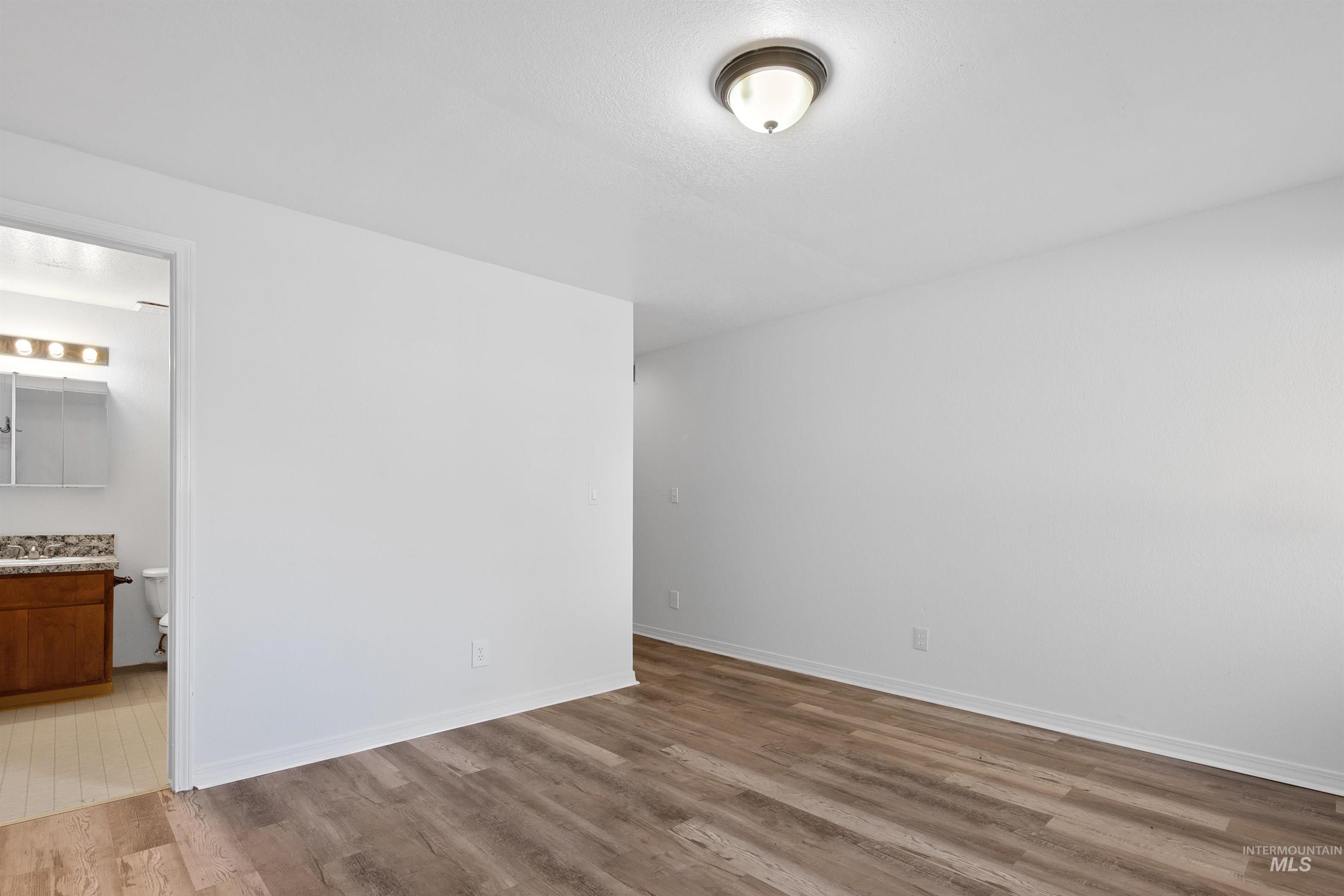 Unfurnished bedroom with light wood-style floors and connected bathroom