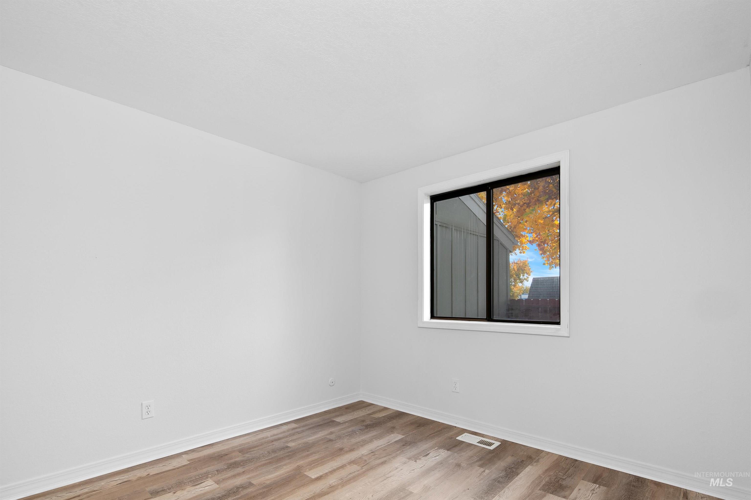 Unfurnished room featuring light wood finished floors and baseboards