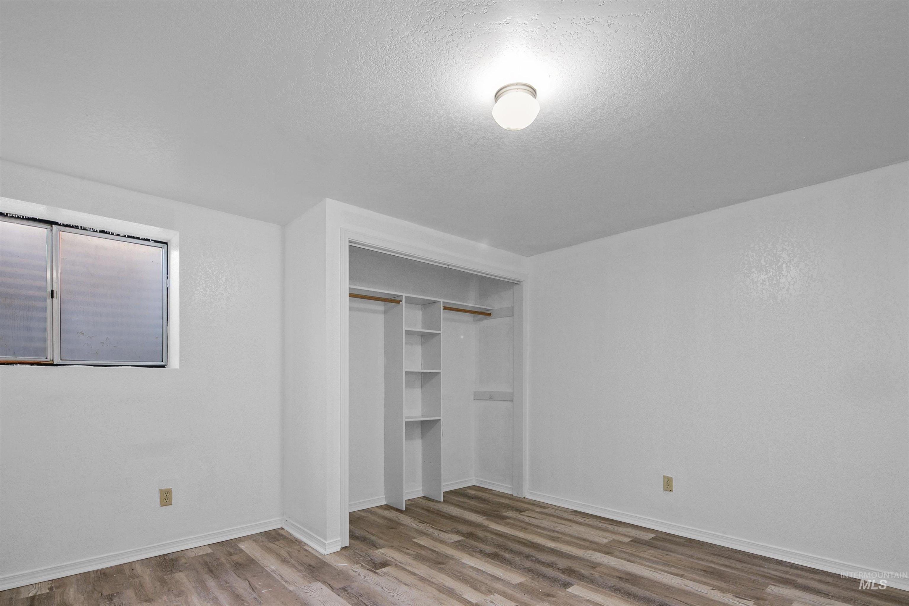 Unfurnished bedroom with a textured ceiling, light wood-style floors, and a closet