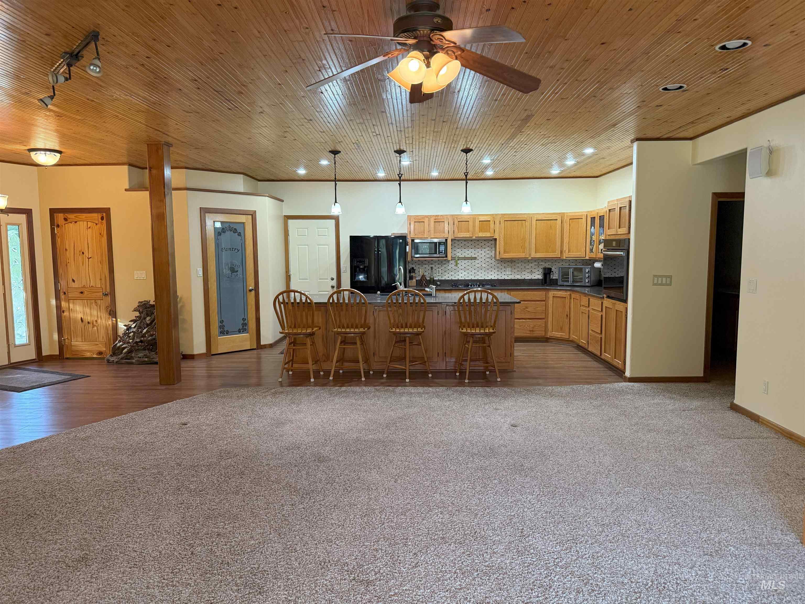 Kitchen featuring dark countertops, a kitchen breakfast bar, a kitchen island, dark carpet, and decorative backsplash