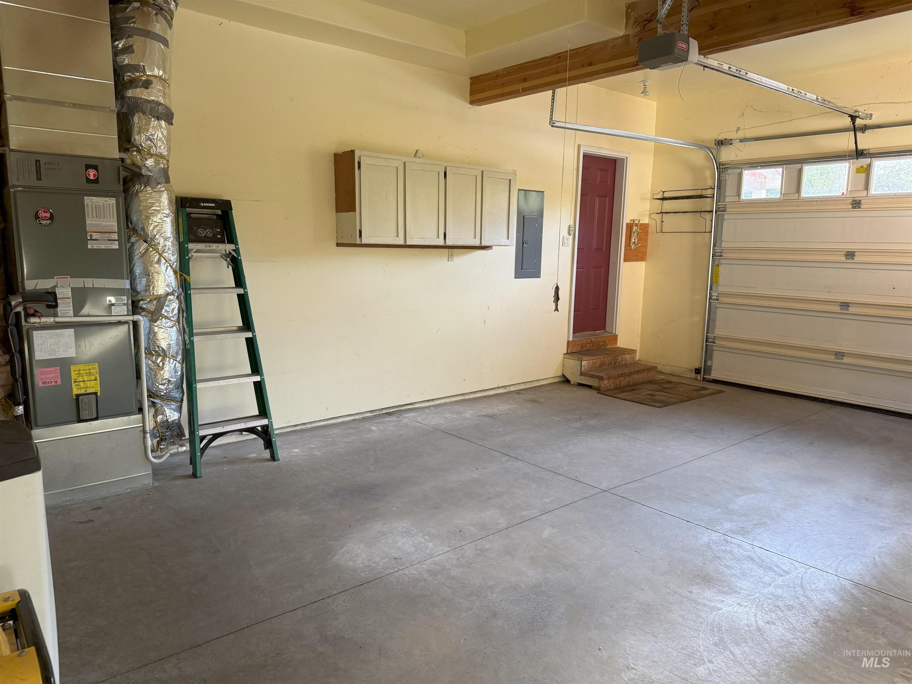 Garage featuring heating unit, electric panel, and a garage door opener