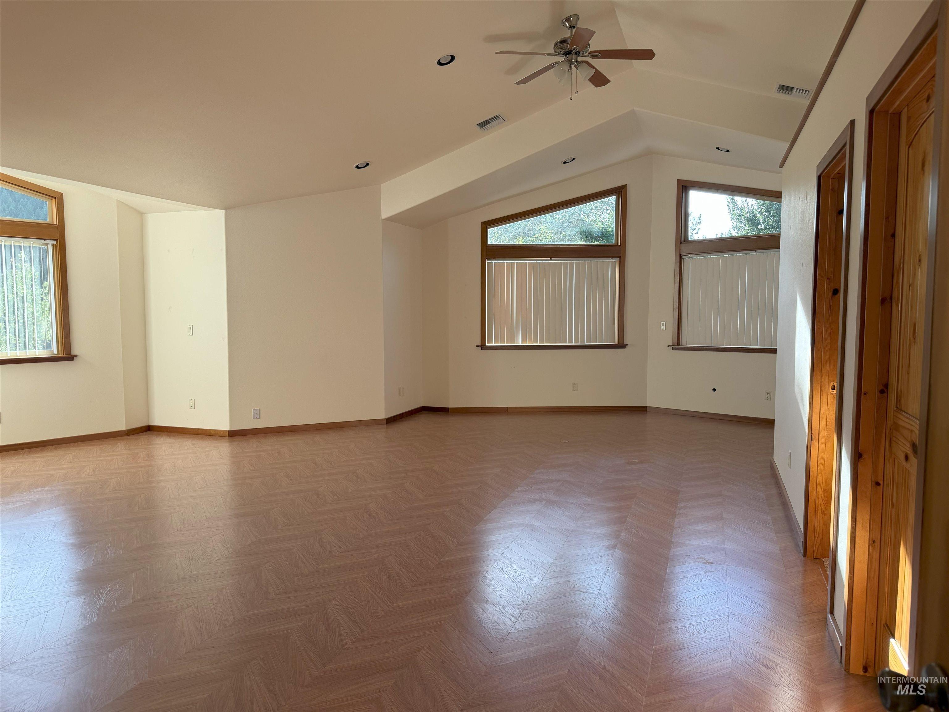 Spare room featuring vaulted ceiling and ceiling fan