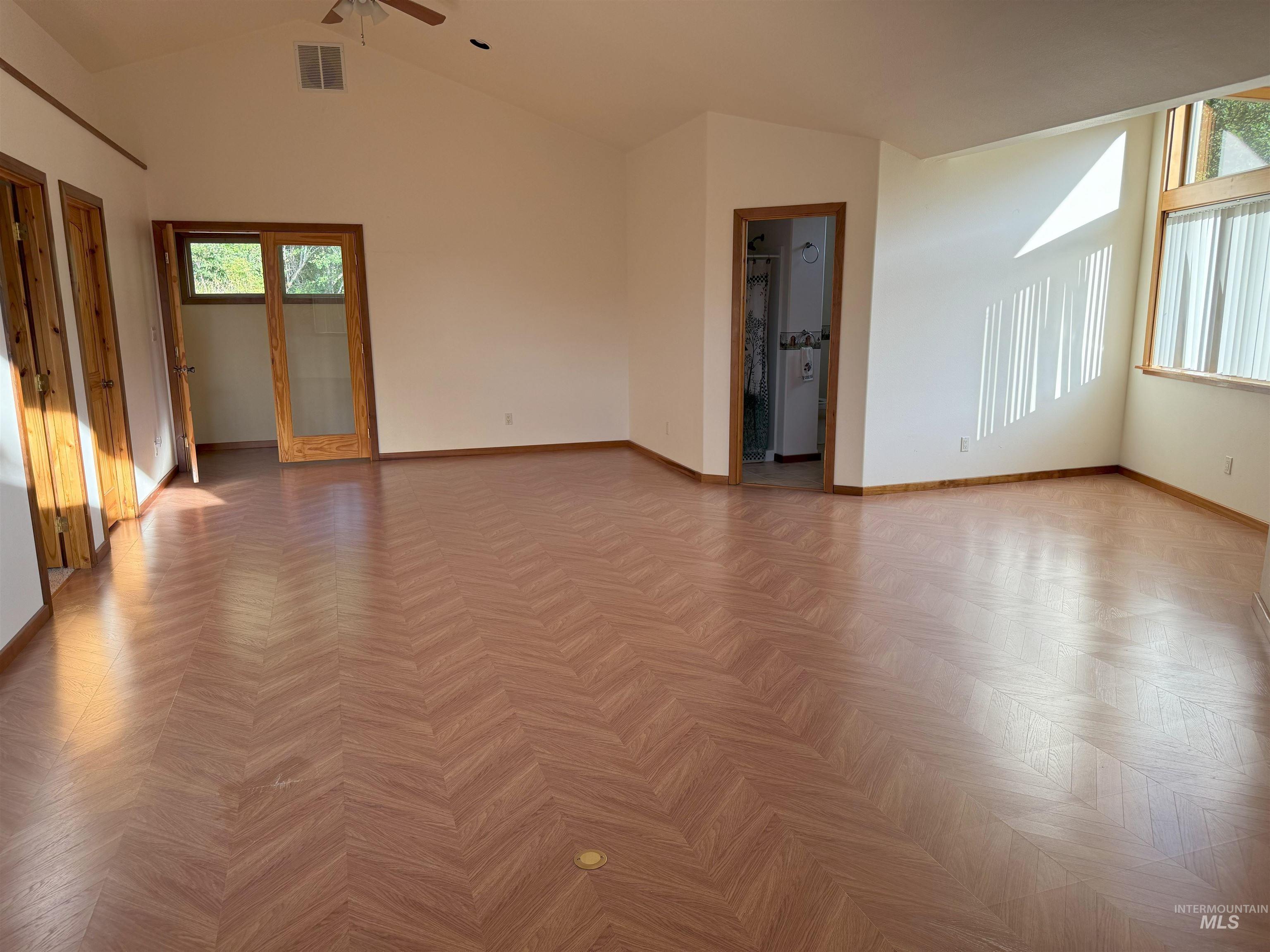Empty room featuring healthy amount of natural light and high vaulted ceiling