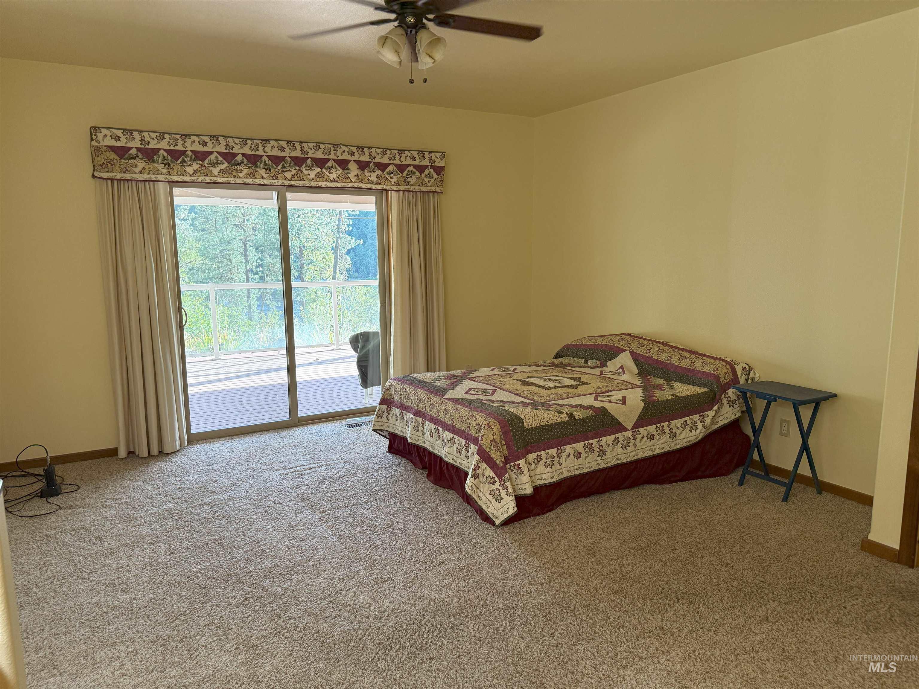 Carpeted bedroom featuring access to exterior and ceiling fan
