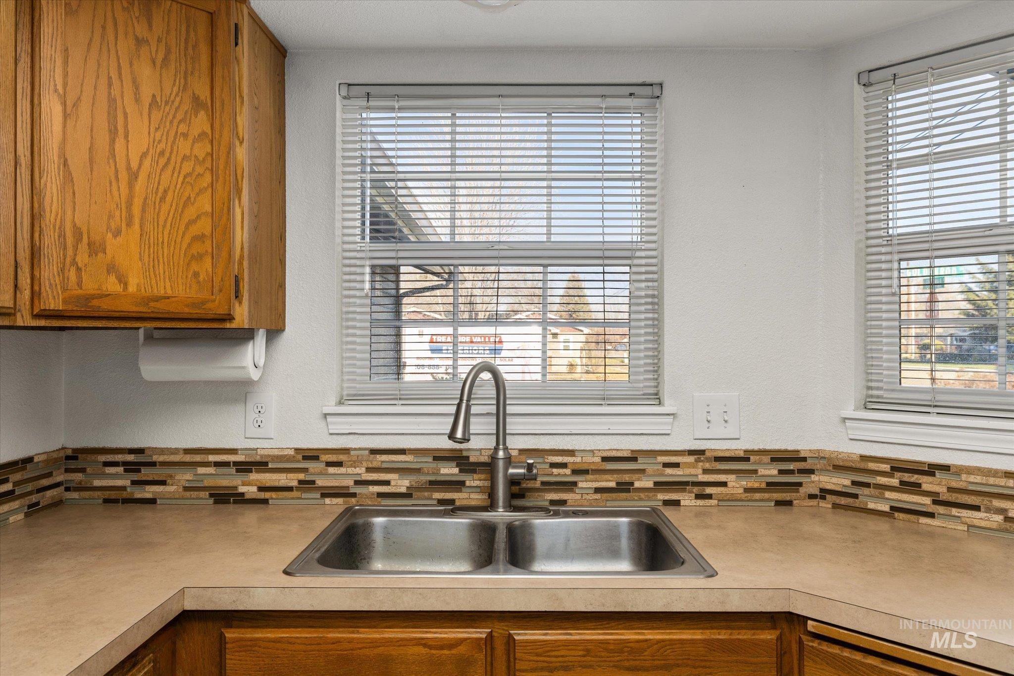 Kitchen featuring brown cabinets, light countertops, and decorative backsplash