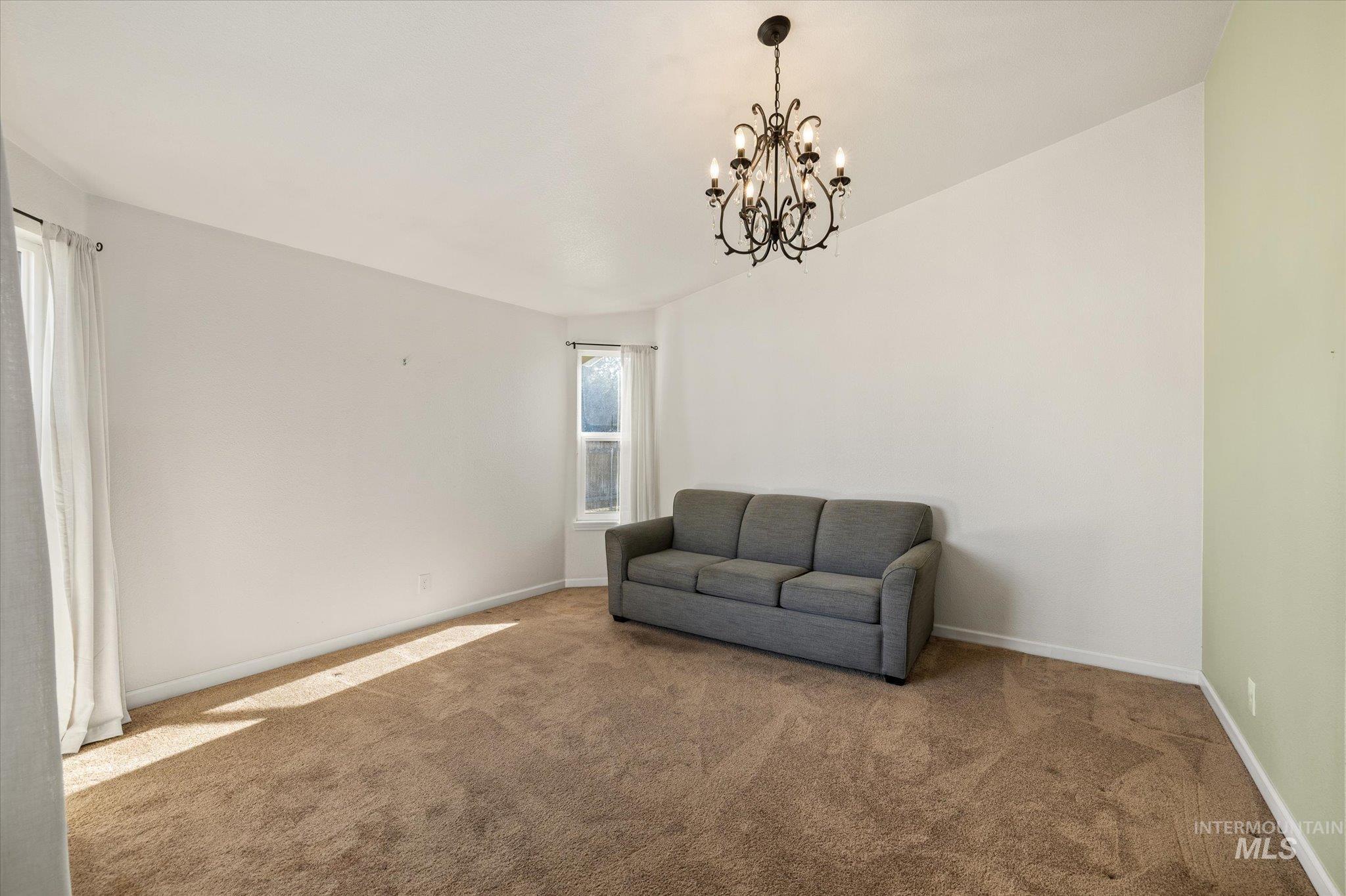 Unfurnished room featuring carpet flooring, lofted ceiling, and a chandelier