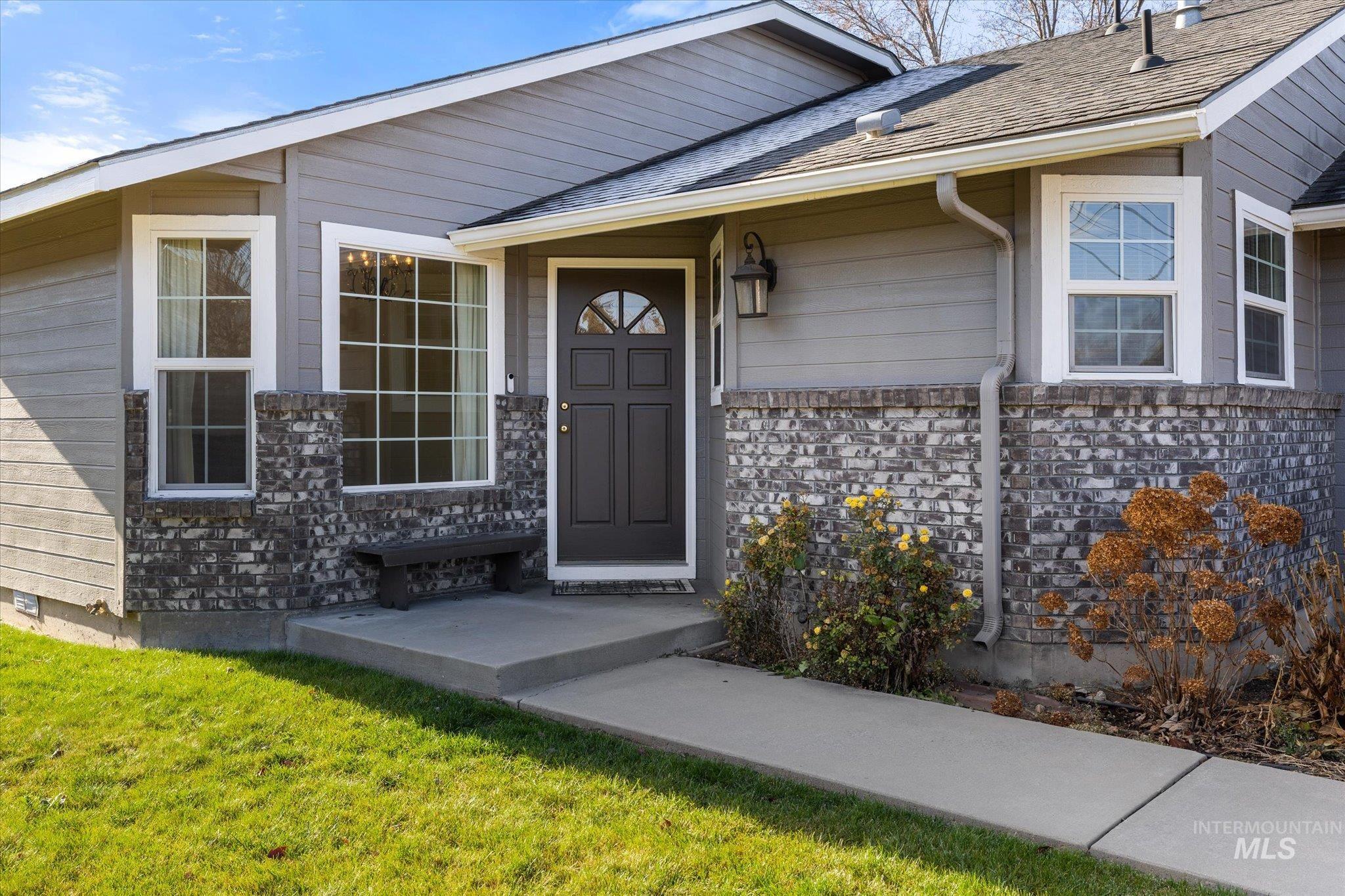 Entrance to property featuring a yard and roof with shingles