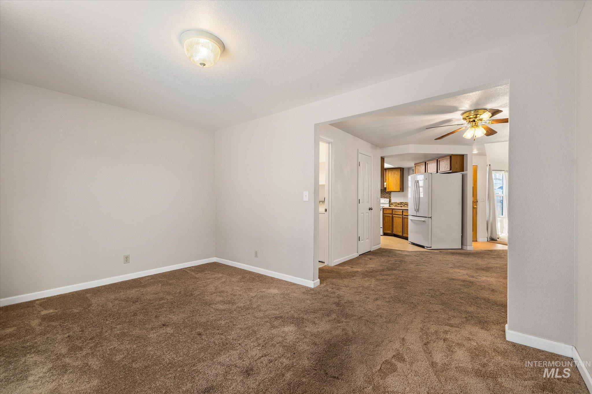 Unfurnished living room featuring dark carpet and a ceiling fan