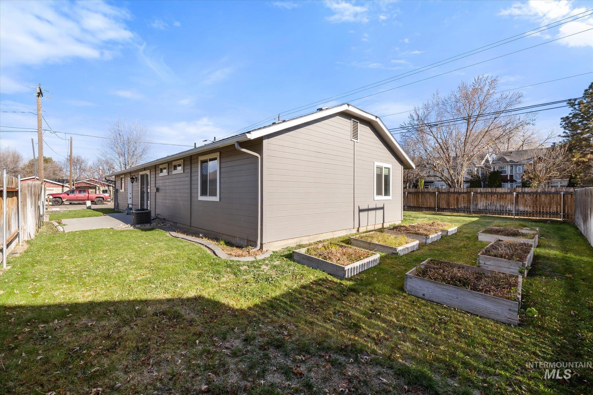 View of side of property featuring a fenced backyard and a garden