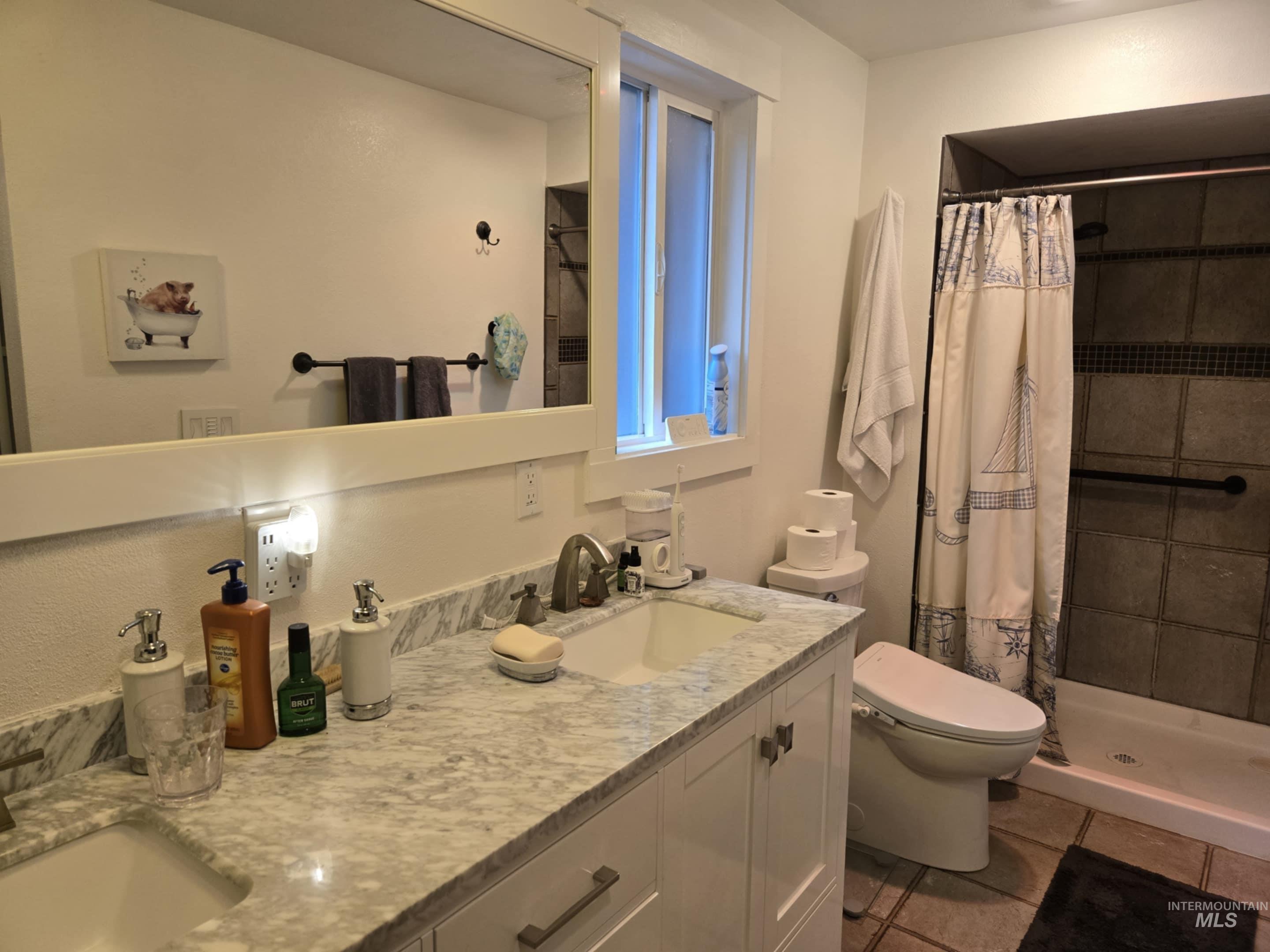 A stone countertop and dual vanity set the tone, while a tiled walk-in shower and window make the bathroom both stylish and bright