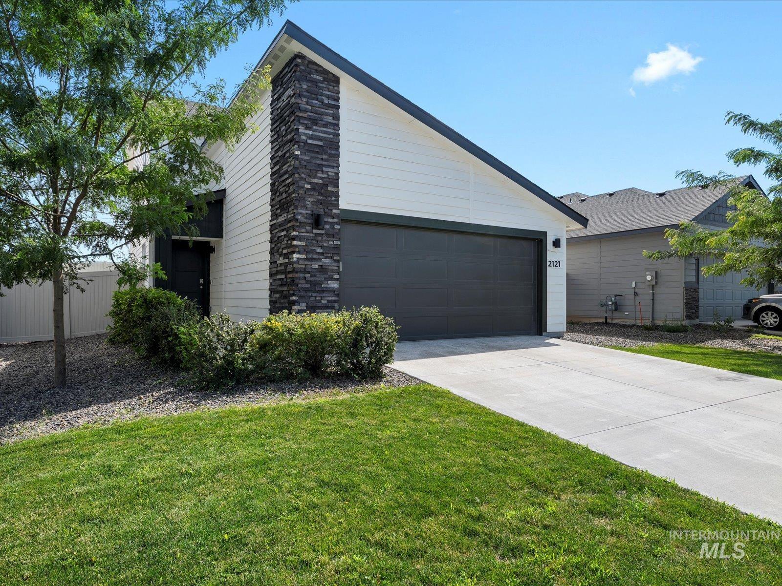 View of front facade with driveway, a front yard, and an attached garage