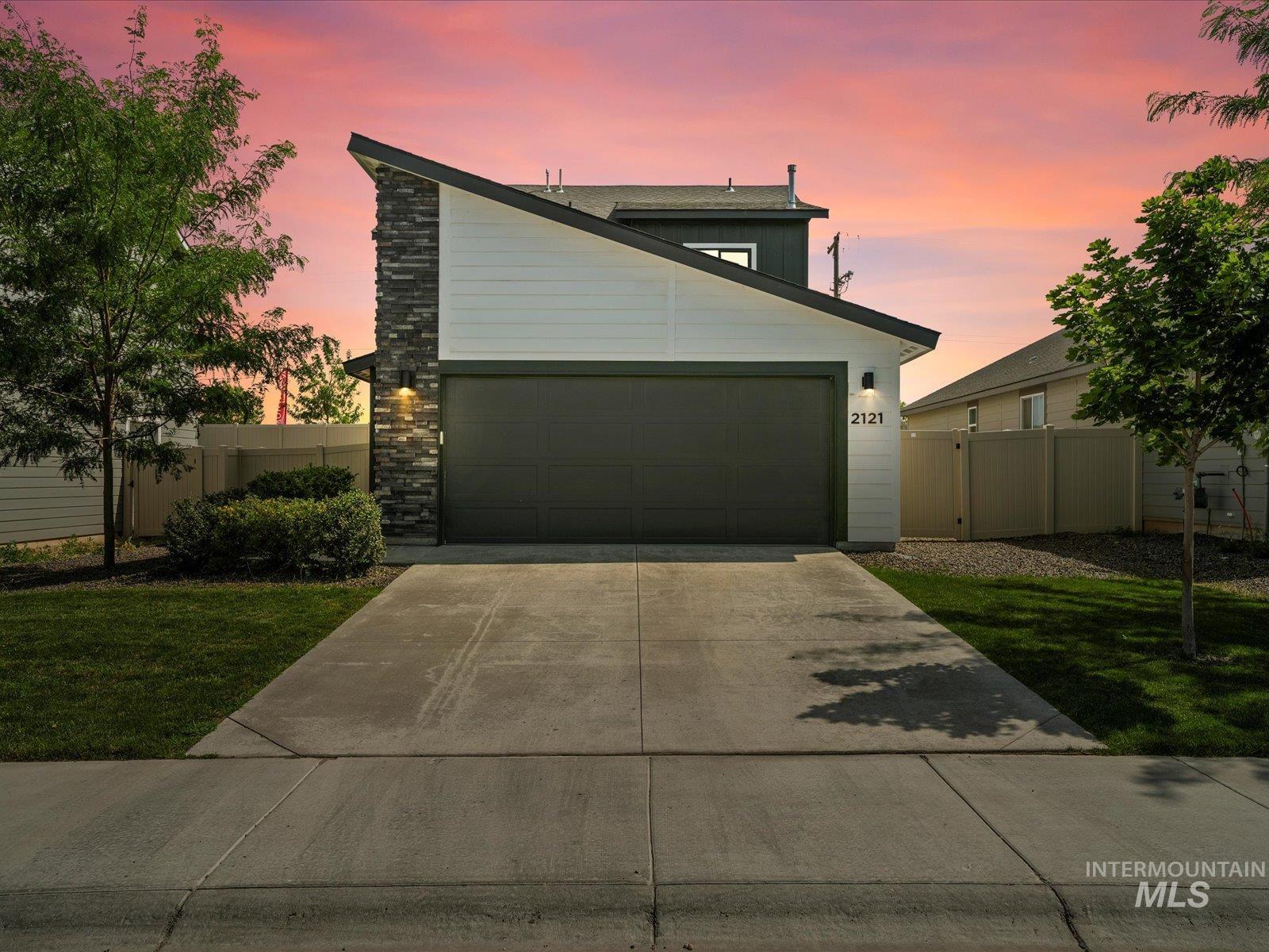 Mid-century modern home featuring concrete driveway, stone siding, and an attached garage