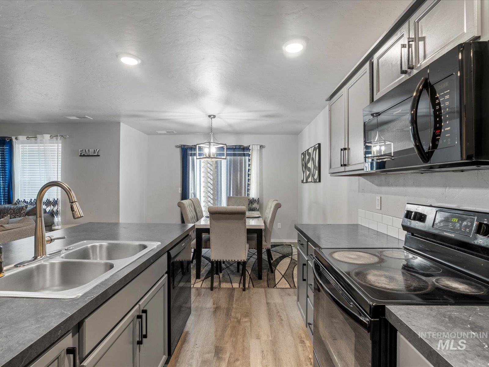 Kitchen with black appliances, dark countertops, healthy amount of natural light, light wood-type flooring, and recessed lighting