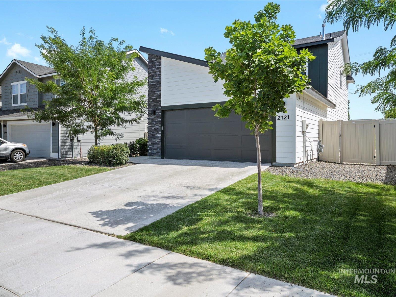 View of front facade featuring a front lawn, driveway, and a gate