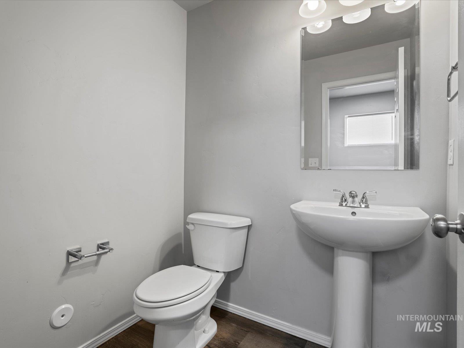 Half bathroom with baseboards and wood finished floors