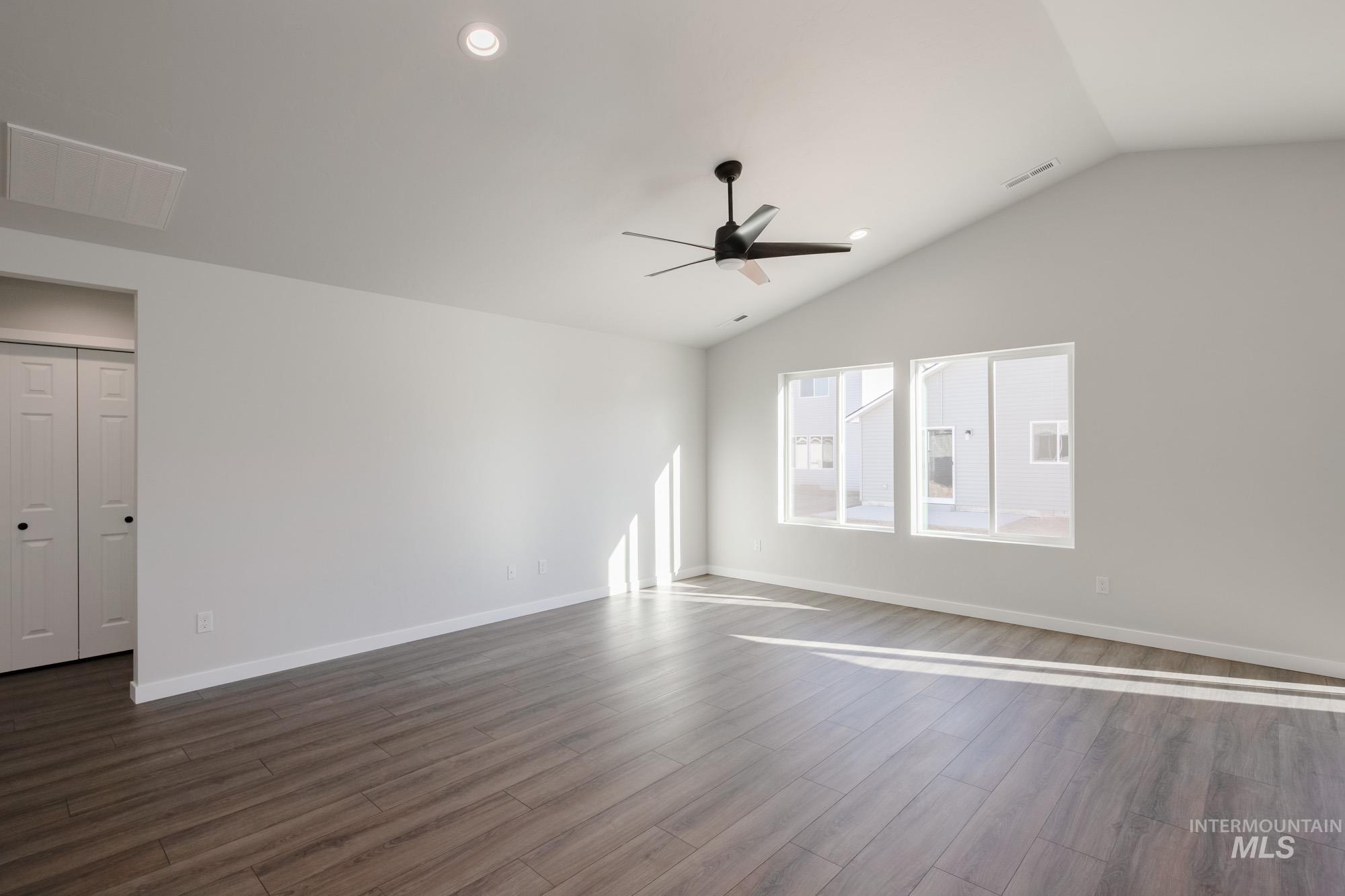 Empty room with dark wood-type flooring, lofted ceiling, recessed lighting, and a ceiling fan