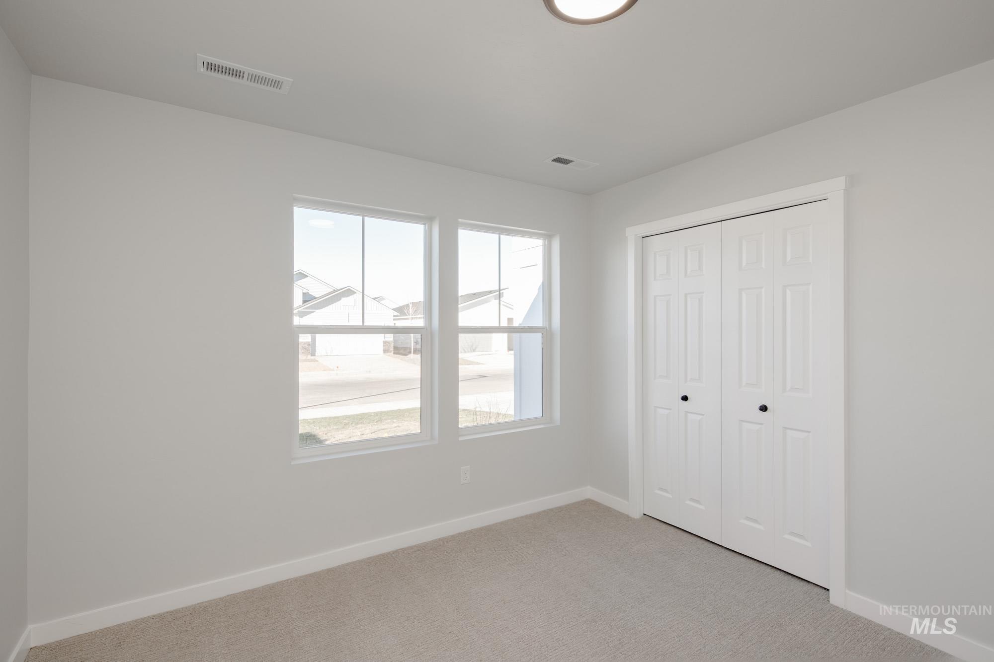 Unfurnished bedroom featuring light carpet and a closet