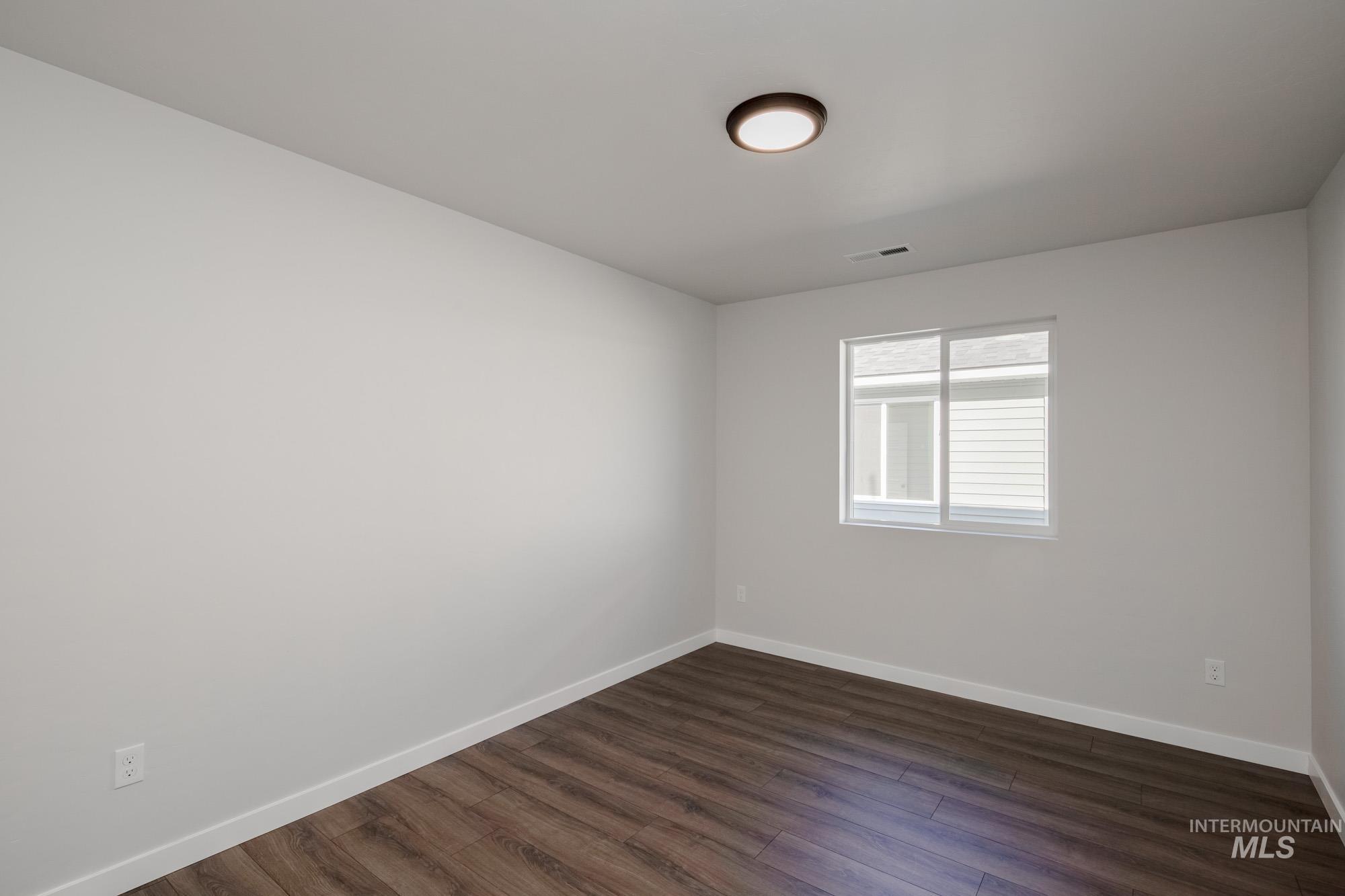 Spare room with baseboards and dark wood-style floors