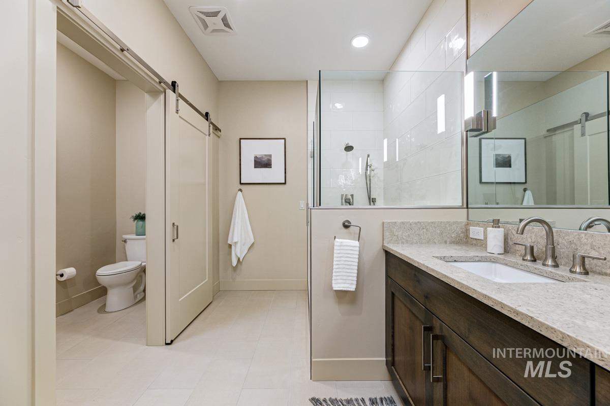 Primary bath featuring vanity, a walk in shower, light tile patterned floors, and recessed lighting