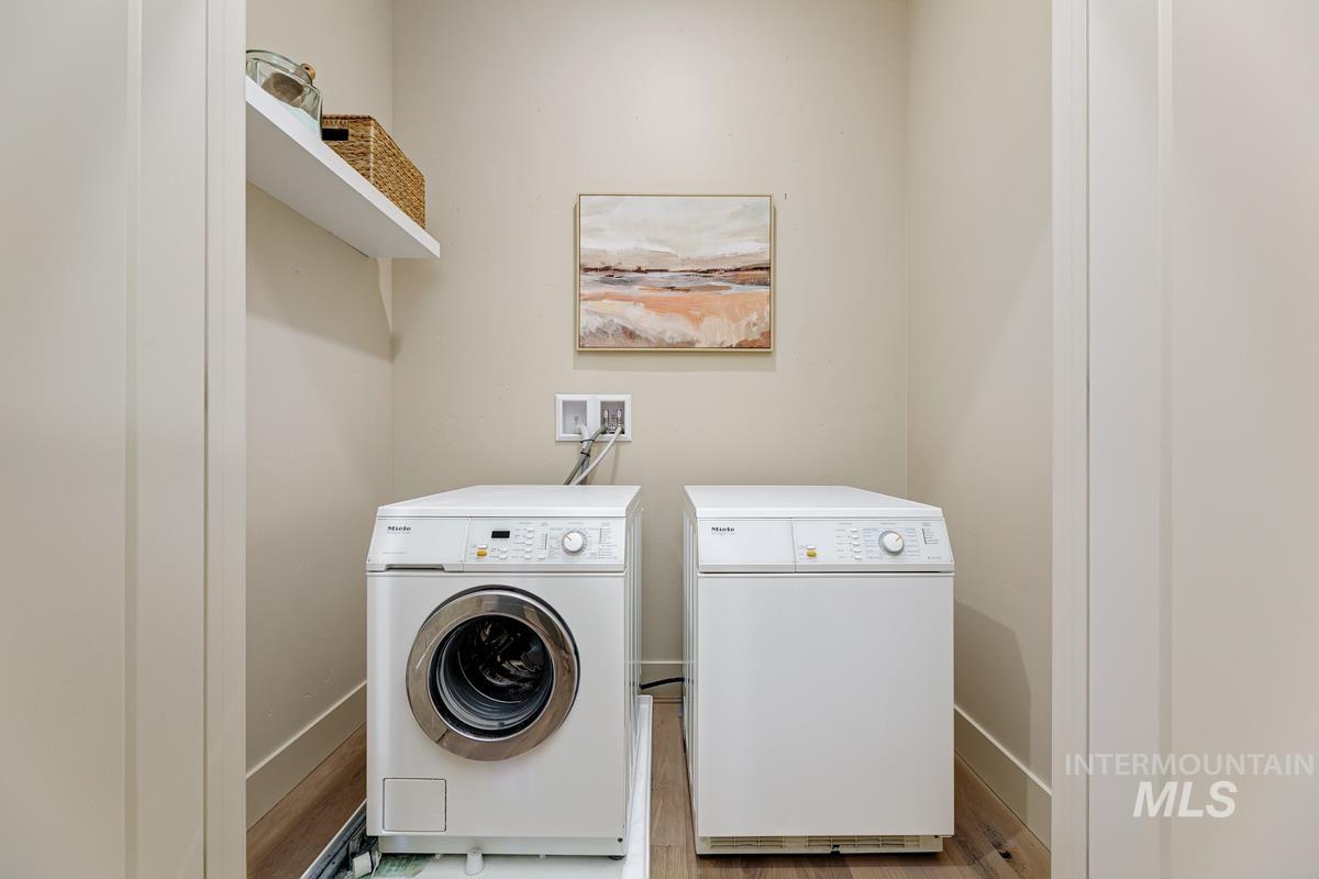 Laundry room with washing machine and dryer and light wood-style flooring