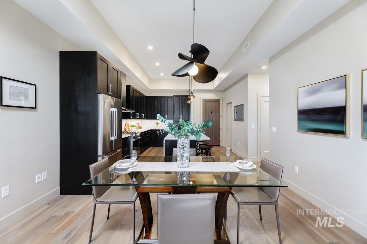Dining area with light wood-type flooring, ceiling fan, a tray ceiling, and recessed lighting