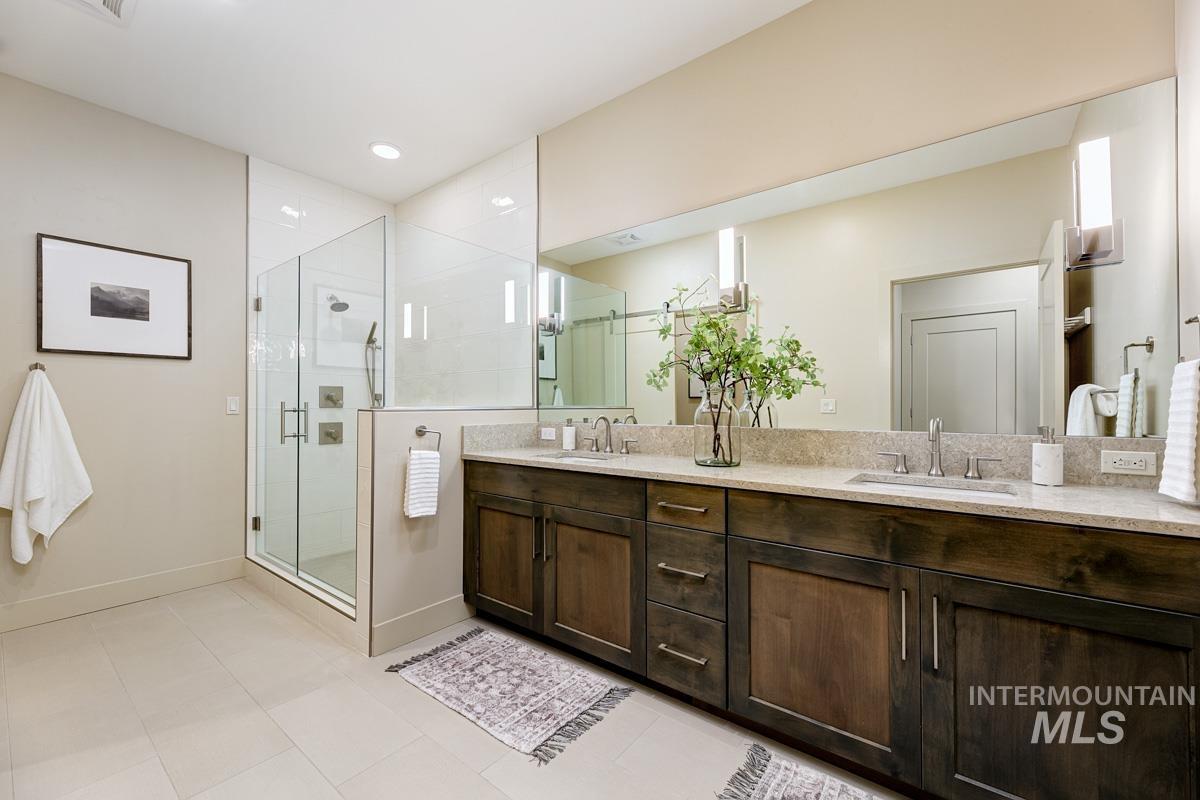 Primary bathroom featuring double vanity, glass & tile walk-in shower, light tile patterned flooring, and recessed lighting
