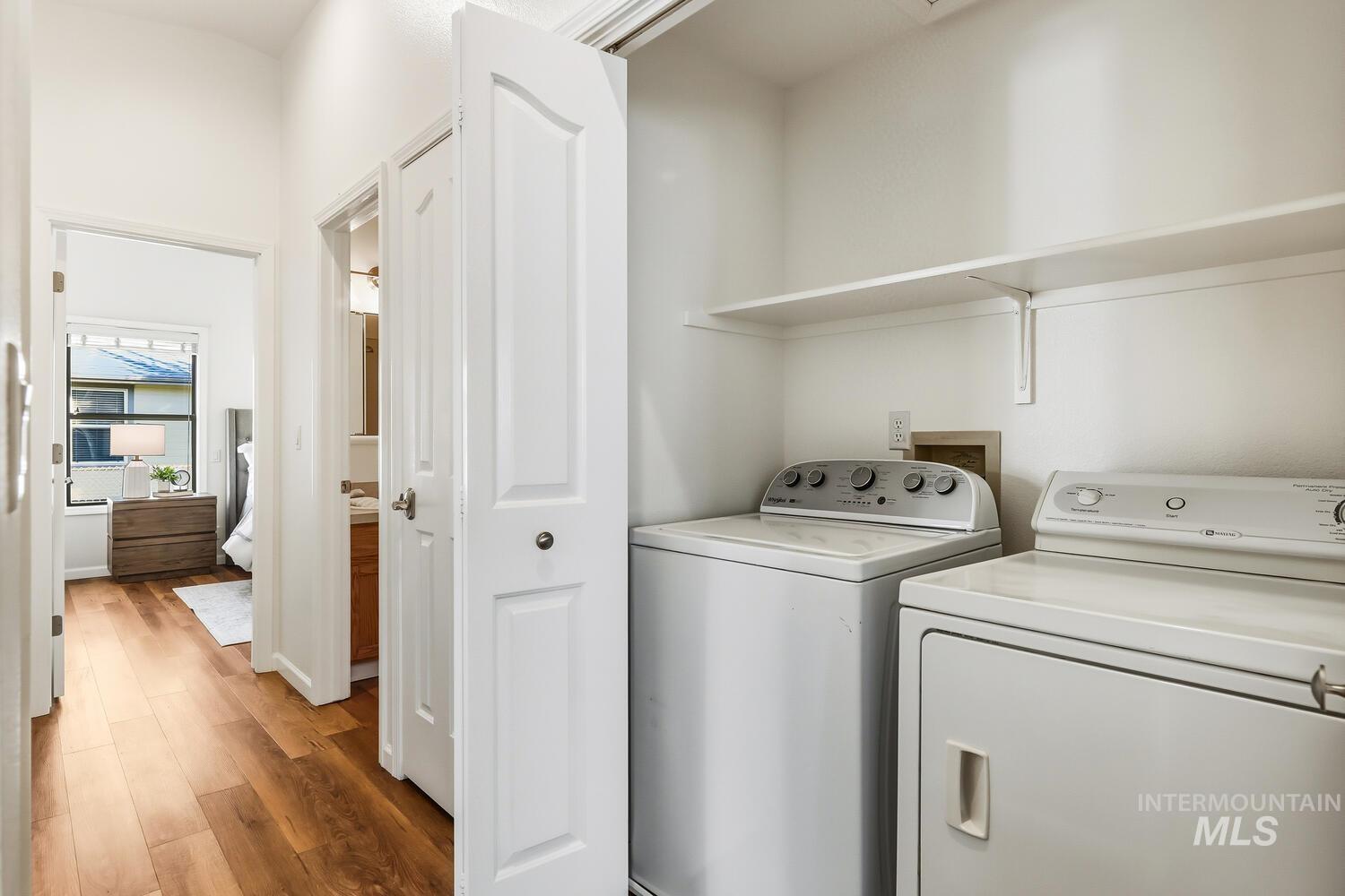Laundry area with wood finished floors and independent washer and dryer