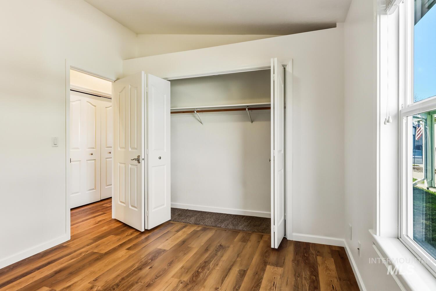 Unfurnished bedroom featuring vaulted ceiling, dark wood finished floors, and a closet