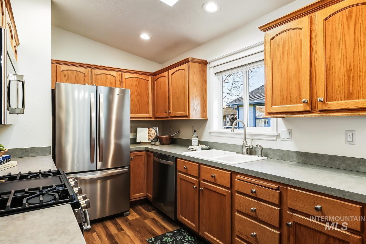 Kitchen with stainless steel appliances, vaulted ceiling, dark wood finished floors, wood finish cabinetry, and recessed lighting