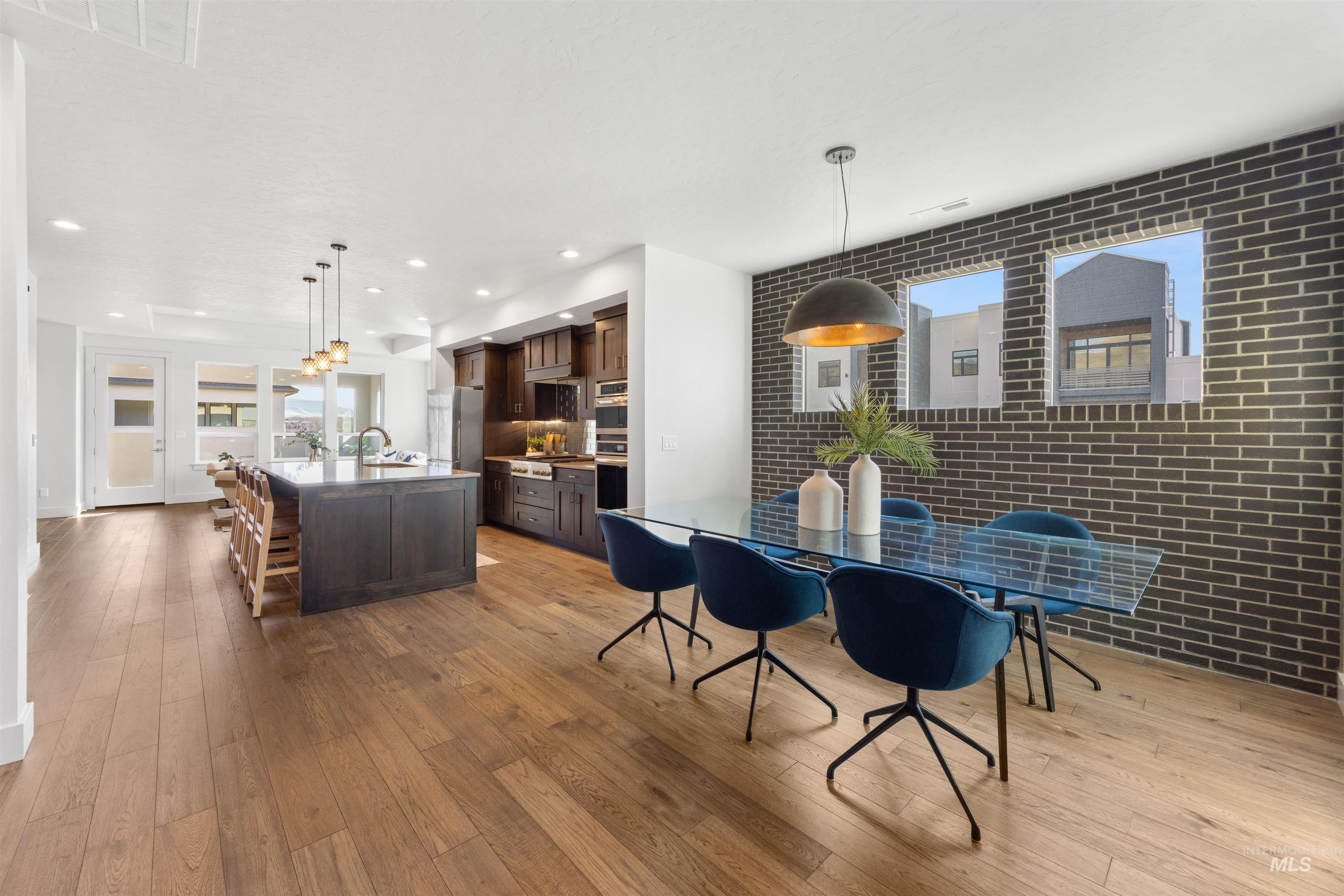 Dining area with brick wall, light wood-style floors, and recessed lighting