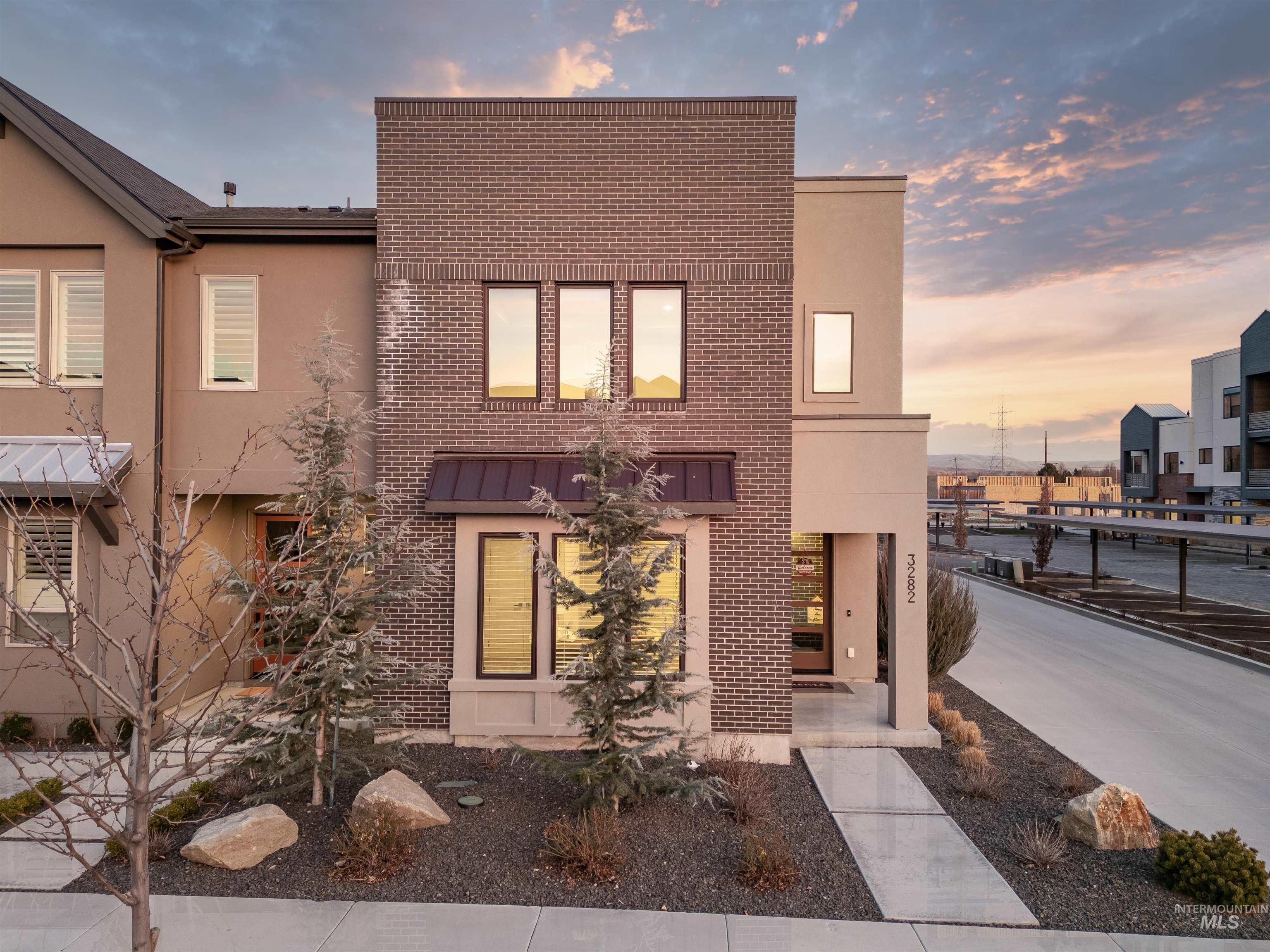 View of front of home with stucco siding, brick siding, and a standing seam roof