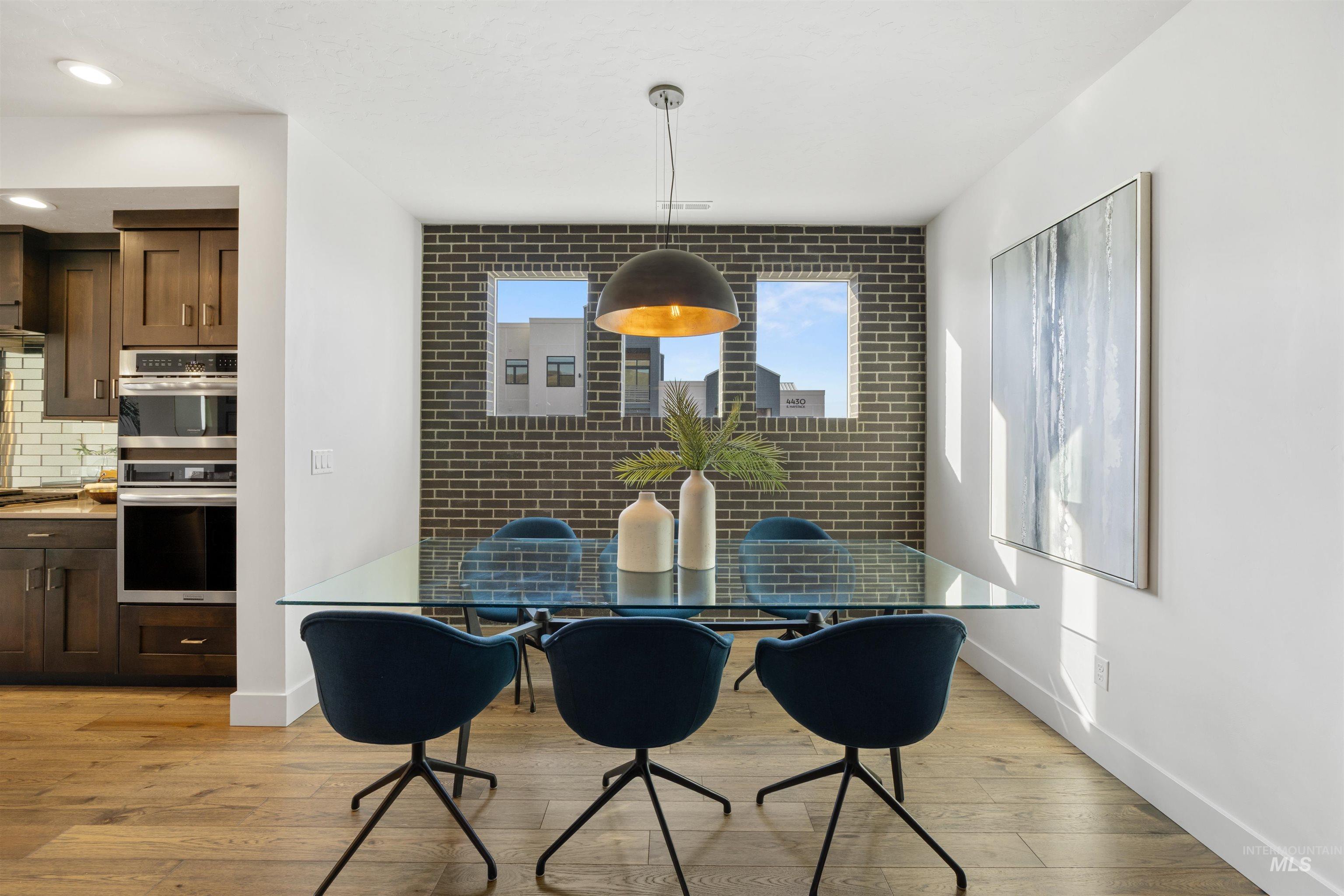 Dining area featuring light wood-style floors, recessed lighting, and brick wall