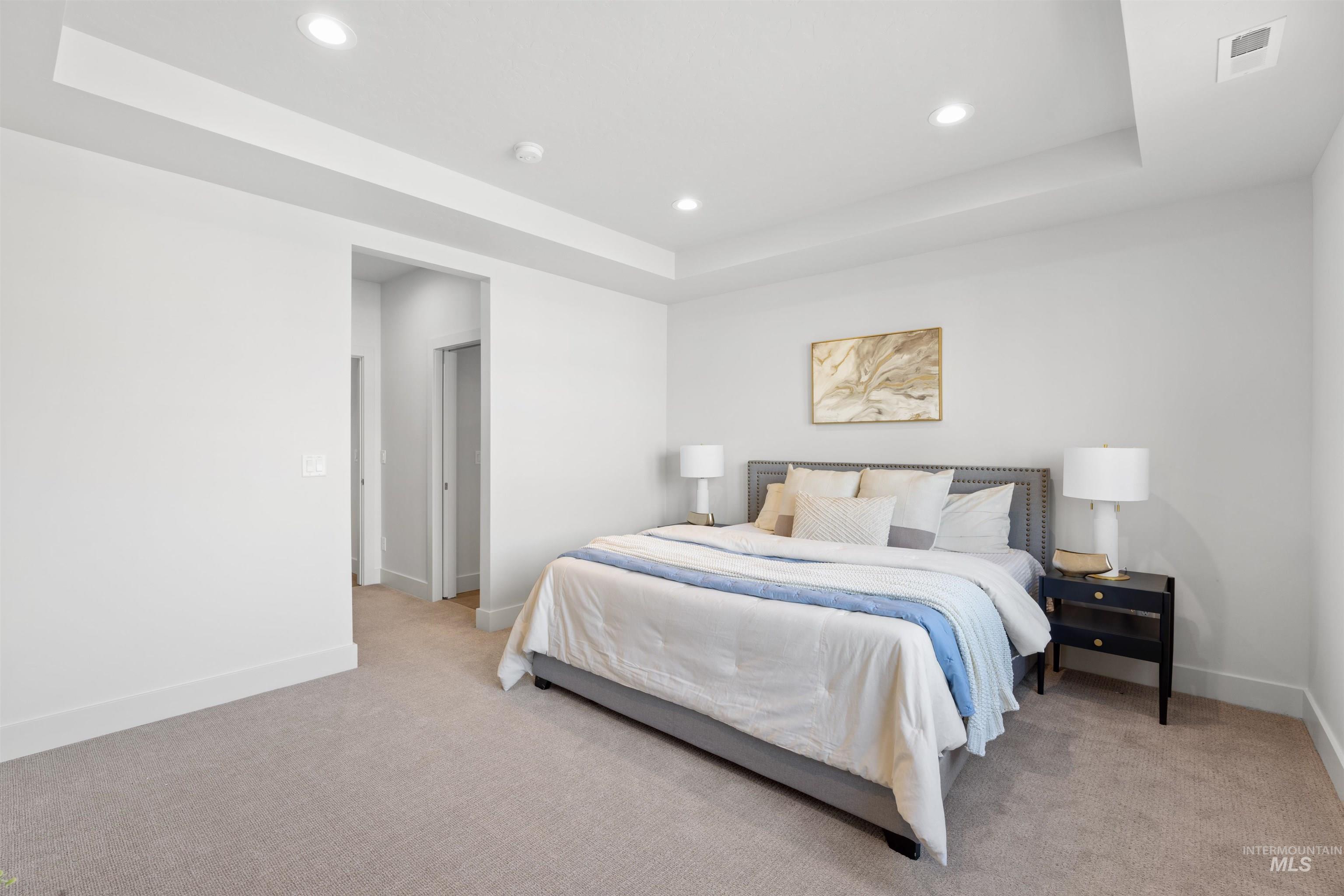 Bedroom featuring a tray ceiling, recessed lighting, and light colored carpet