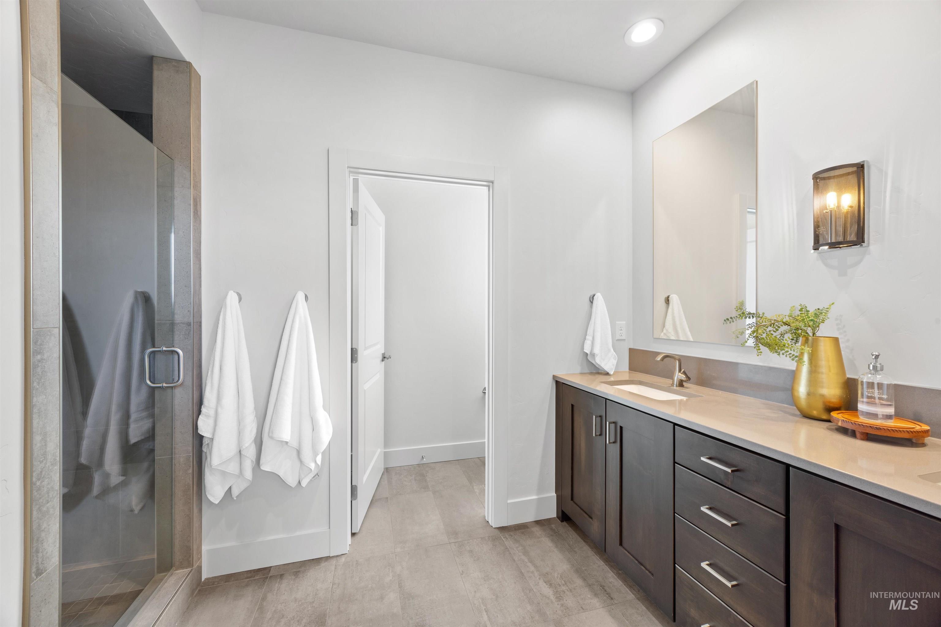 Full bath with double vanity, a stall shower, and recessed lighting
