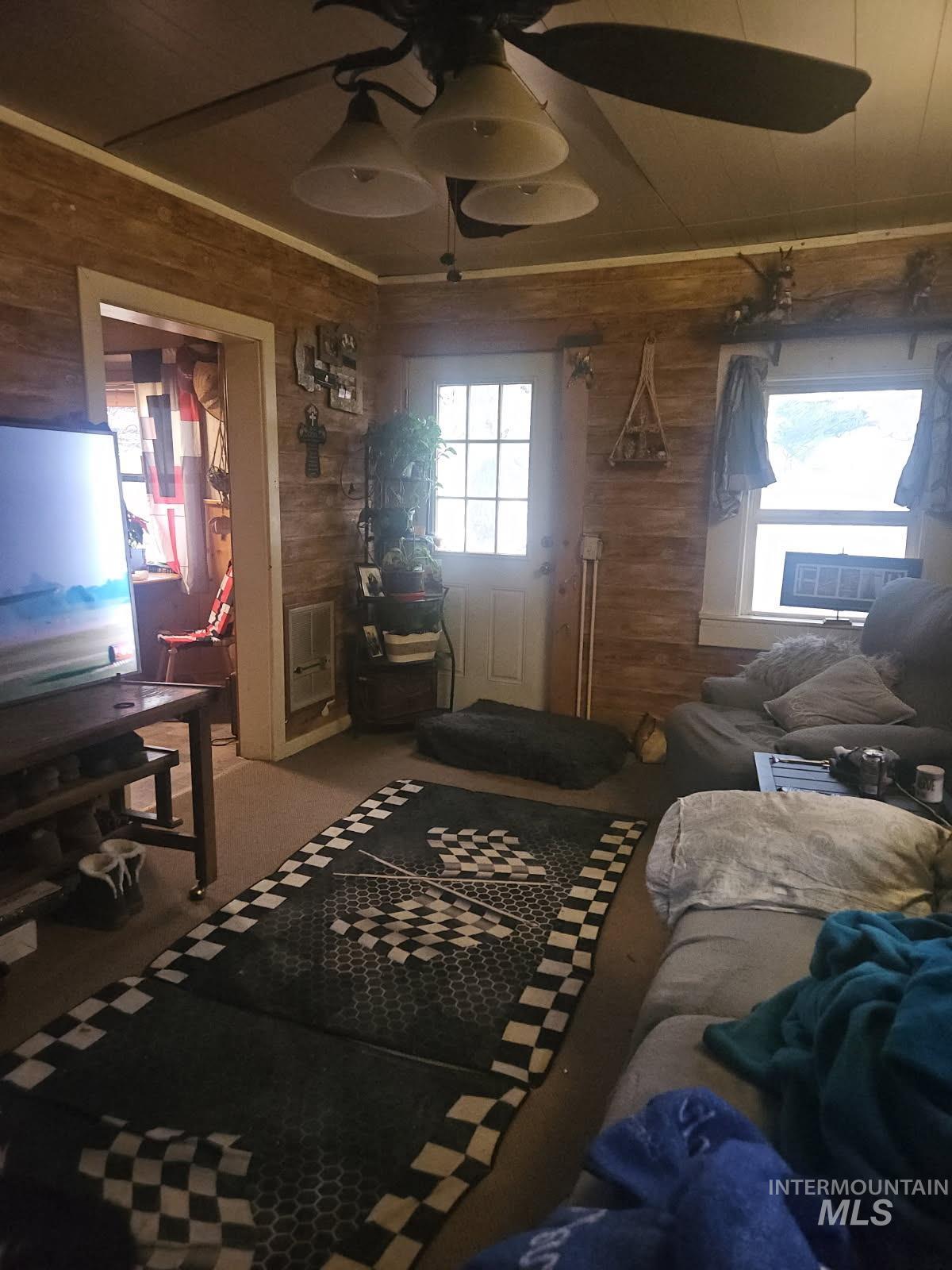 Carpeted bedroom with wood walls, a ceiling fan, and a closet