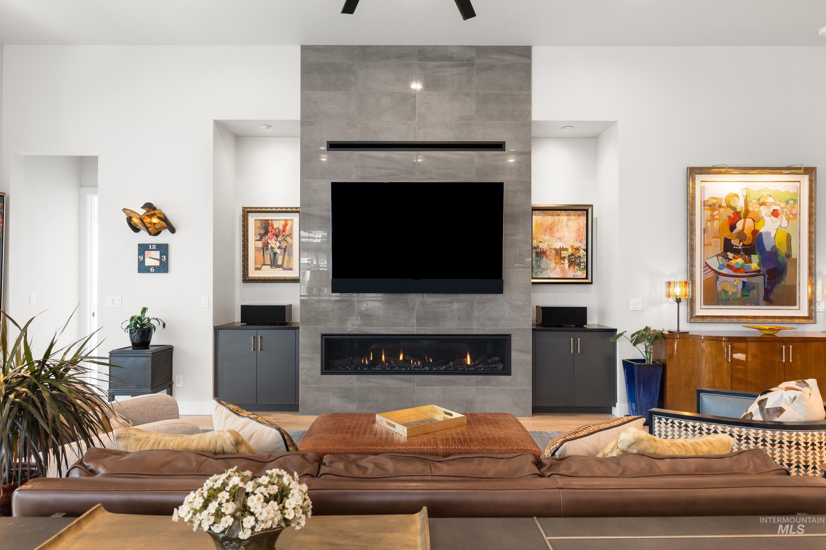 Living area featuring a tiled fireplace, wood finished floors, and ceiling fan