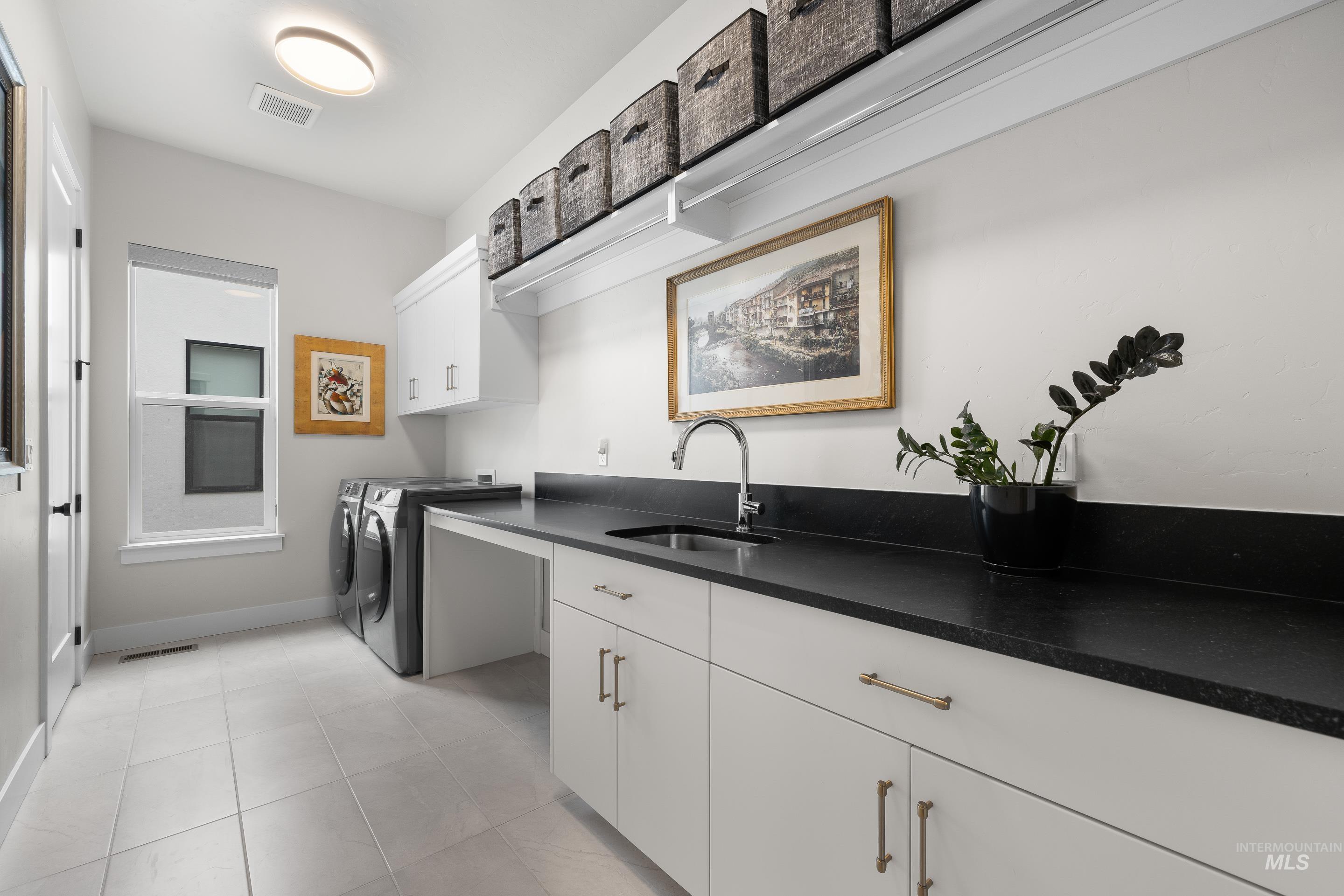 Laundry room with cabinet space, washer and clothes dryer, and light tile patterned floors